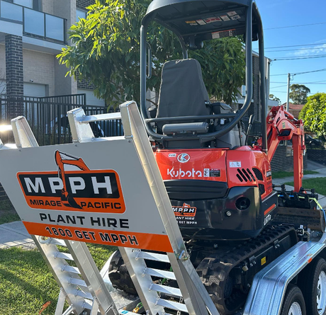 A small excavator is parked on a trailer with a sign that says mpph plant hire