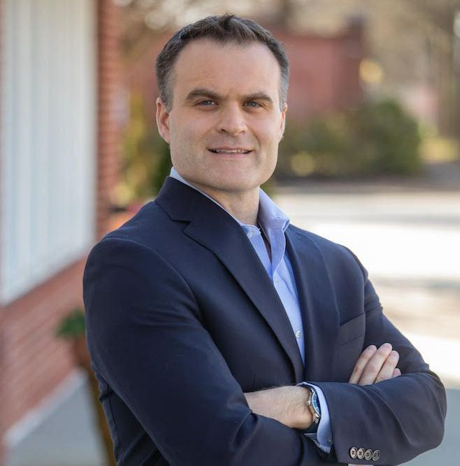 A man in a suit and tie is smiling for the camera.