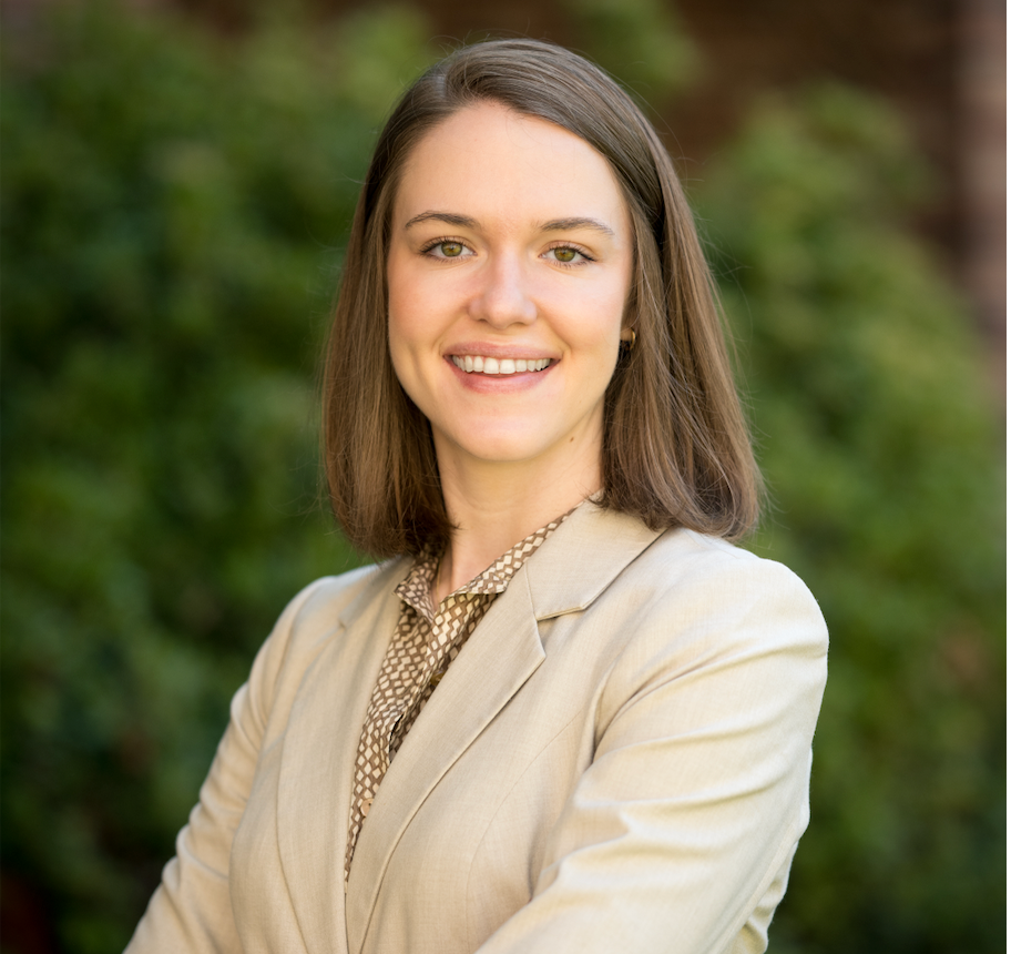 A woman in a white jacket and green shirt is smiling for the camera.