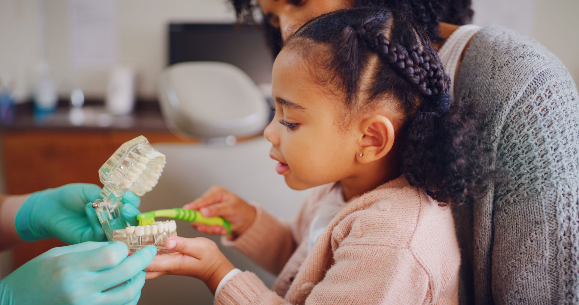 Child learning to brush teeth with a dental model at the dentist
