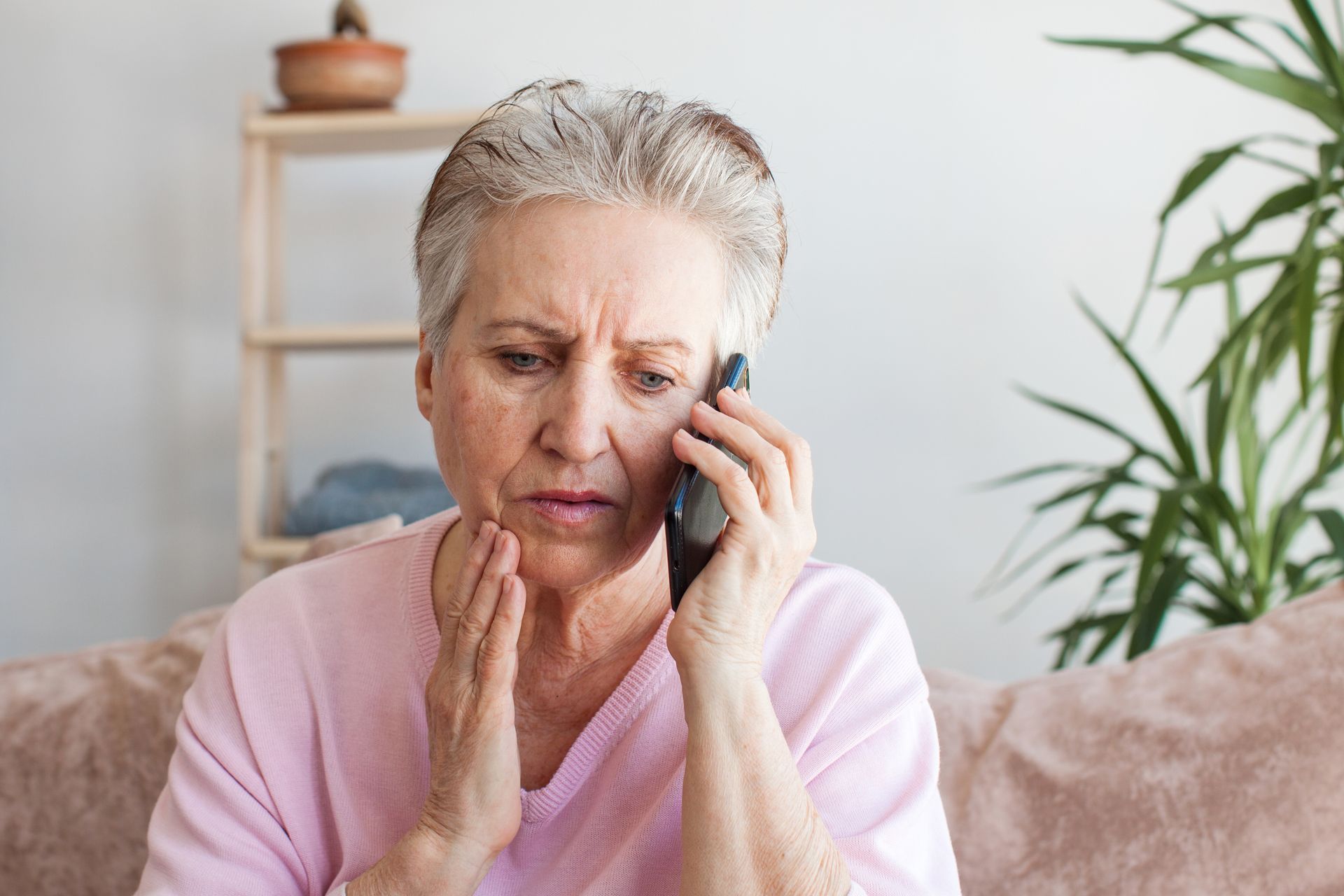 Woman holding her jaw in pain while calling to schedule an emergency dental appointment