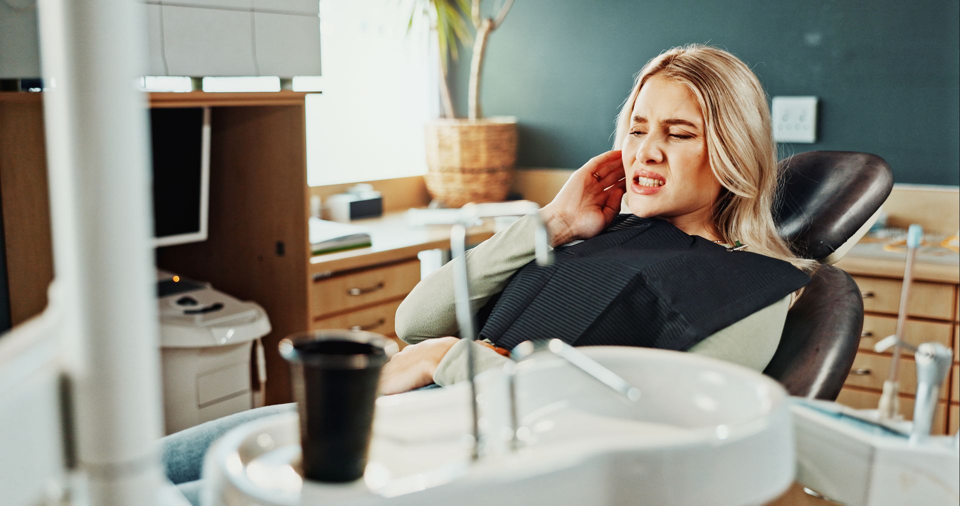 Patient wincing in pain in a dental chair before treatment