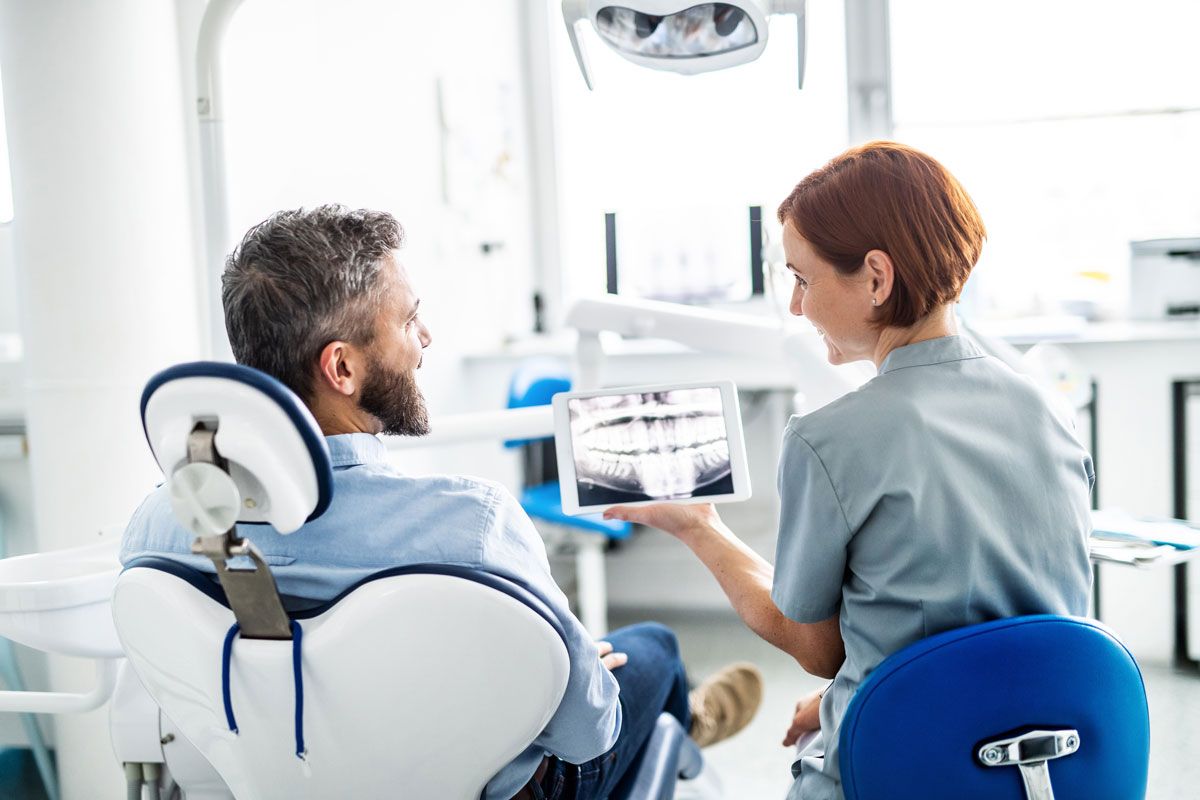 Dentist showing X-ray to seated patient in a bright dental clinic