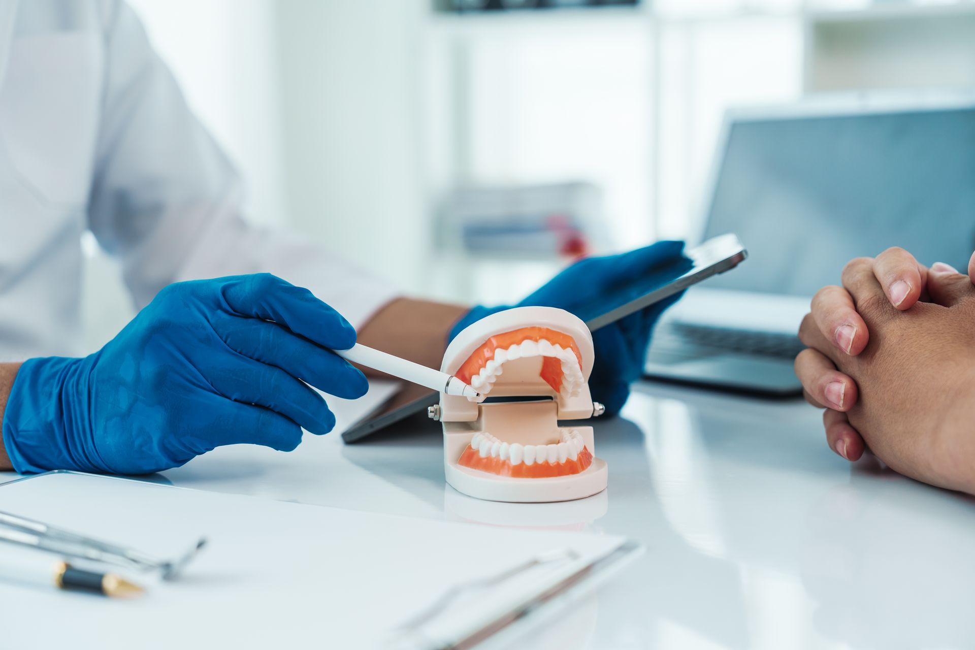 Dentist explaining dental care using a teeth model with a patient