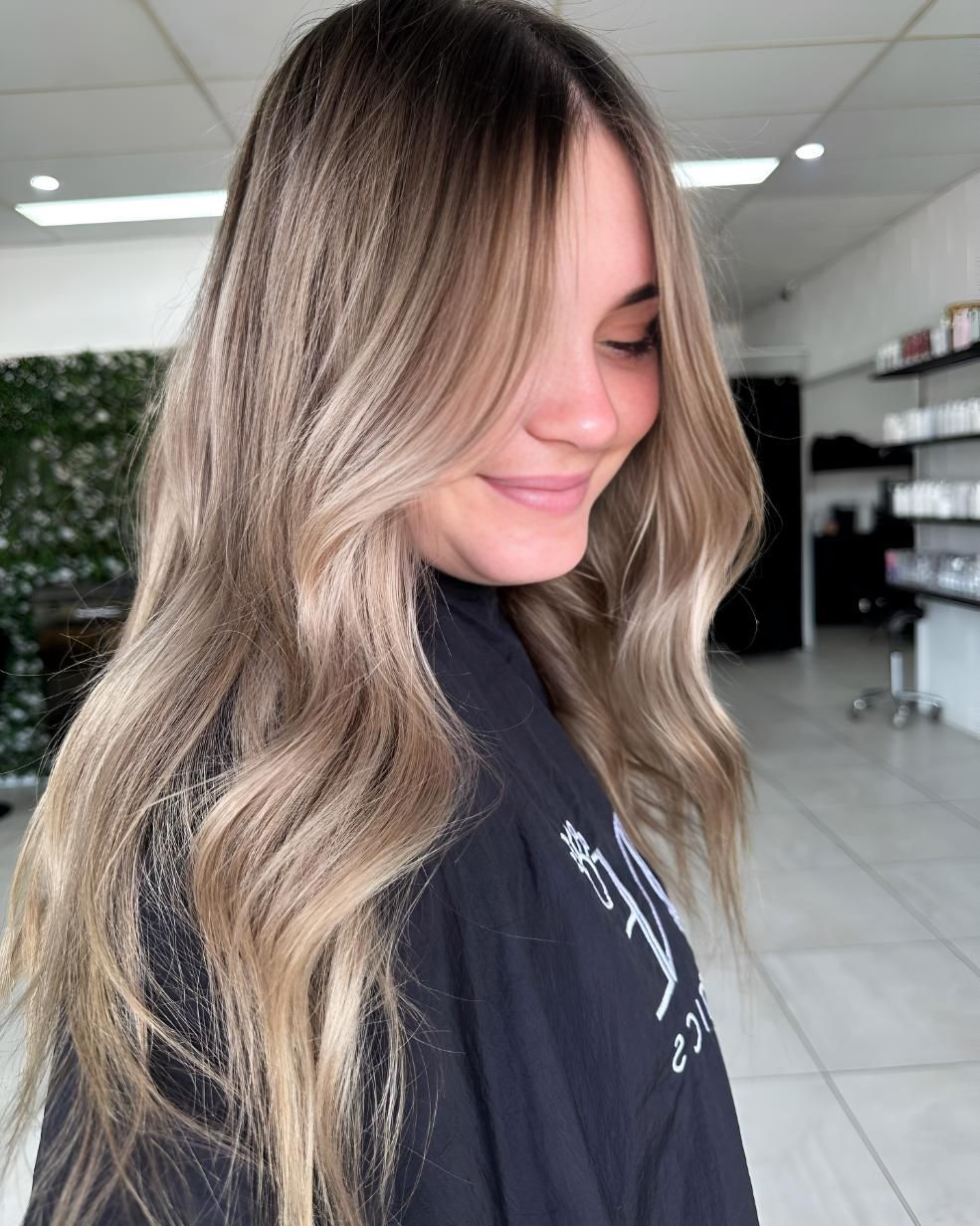 A Woman With Long Blonde Hair Is Smiling — Beautique Hair Lounge & Beauty Bar In Condon, QLD
