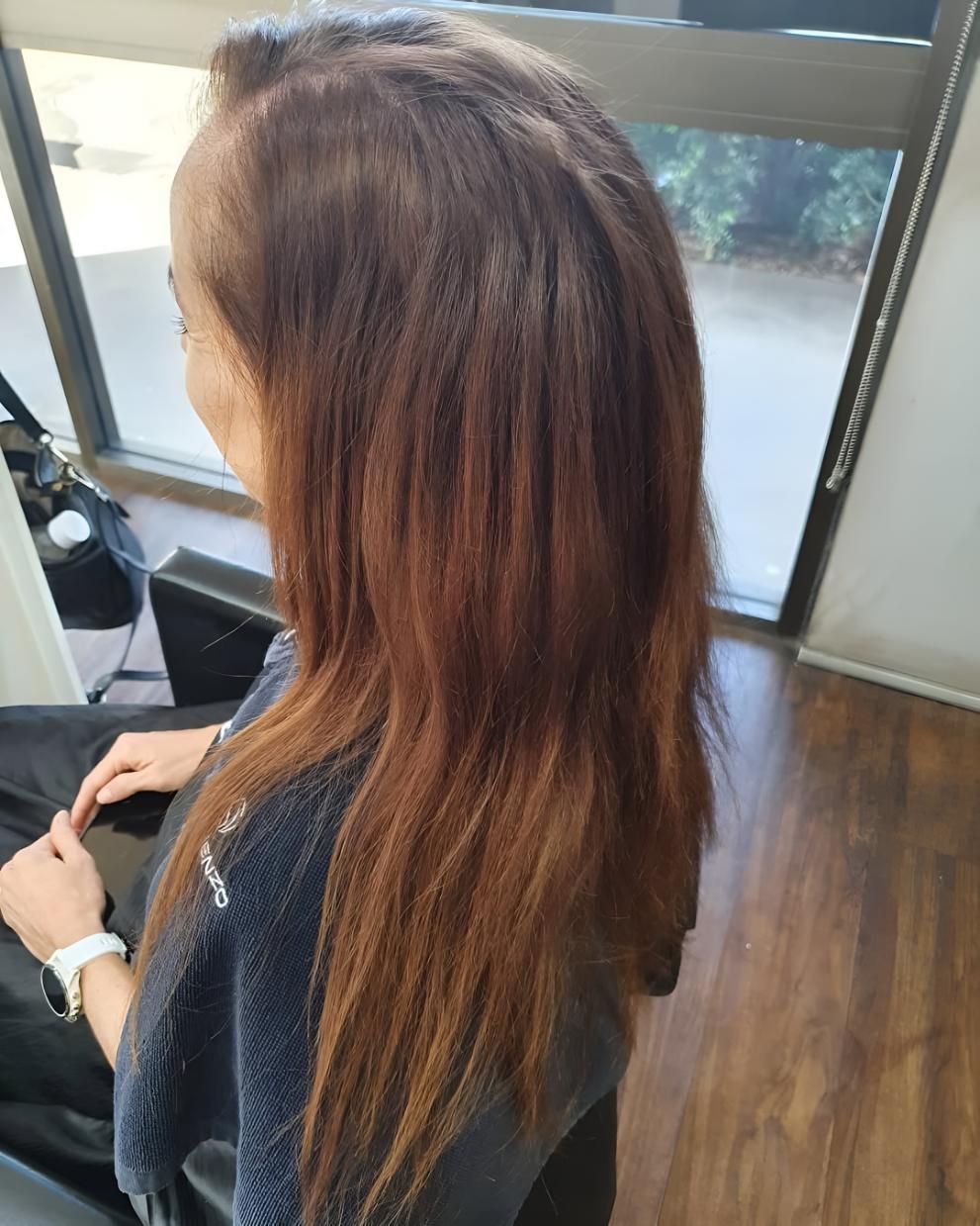 A Woman With Long Brown Hair Is Sitting — Beautique Hair Lounge & Beauty Bar In Condon, QLD