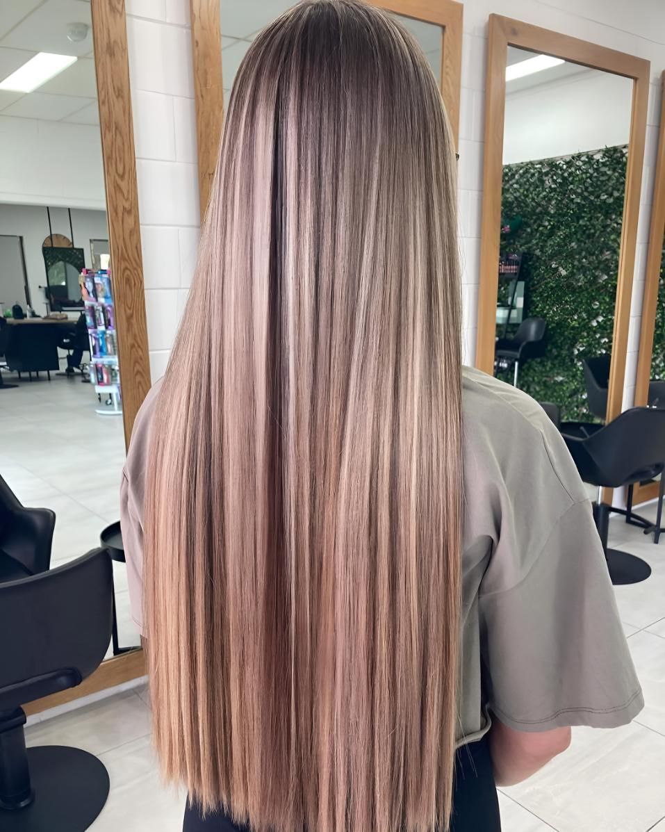 A Woman With Long Hair Is Standing In Front Of A Mirror — Beautique Hair Lounge & Beauty Bar In Charters Towers, QLD