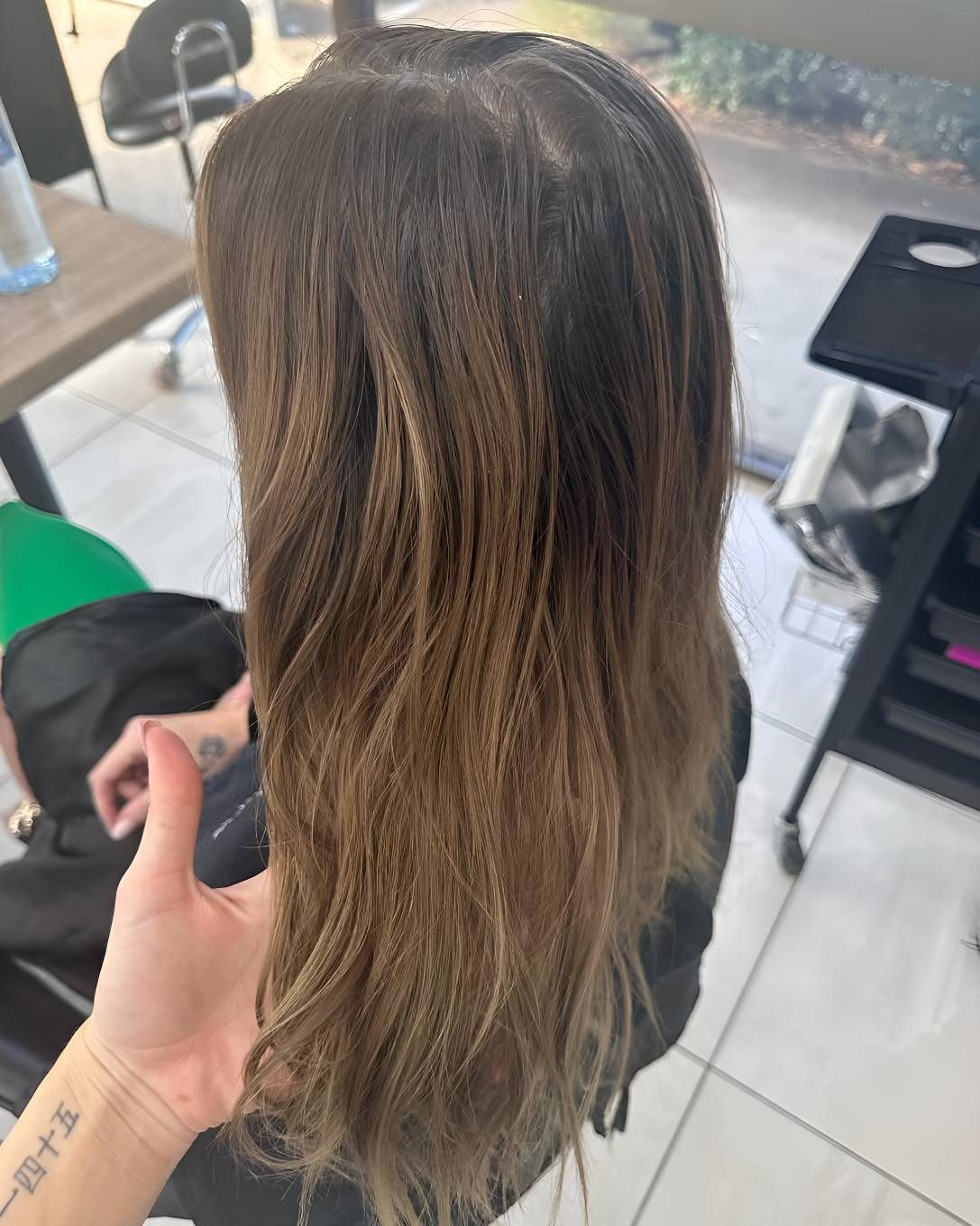 A Woman With Long Brown Hair Is Sitting — Beautique Hair Lounge & Beauty Bar In Rasmussen, QLD