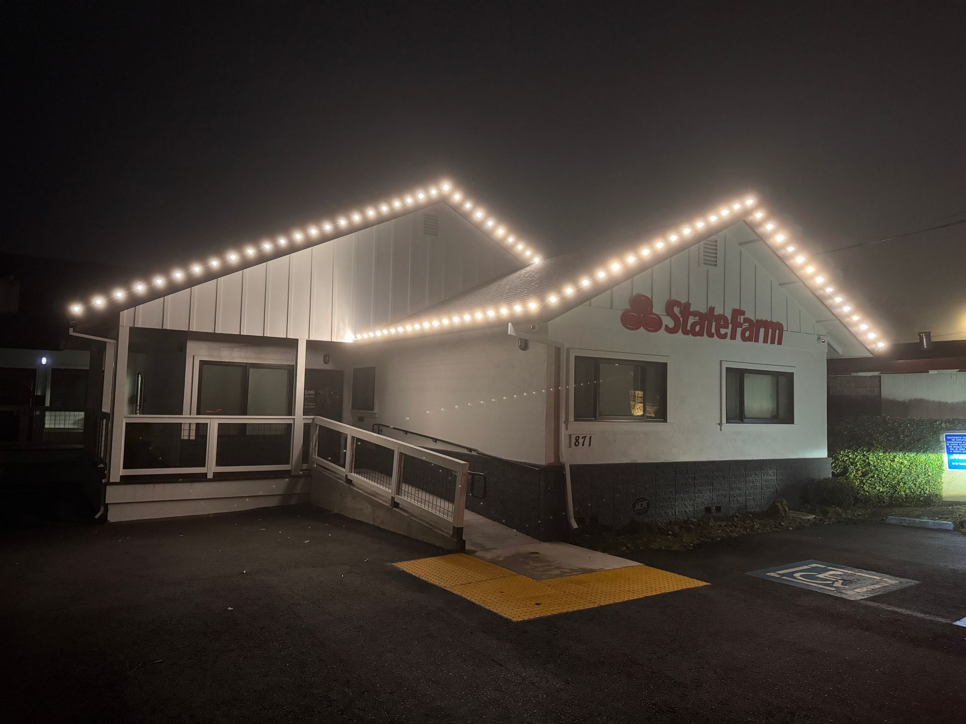 Exterior of a State Farm office at night, with lit roofline and wheelchair ramp.