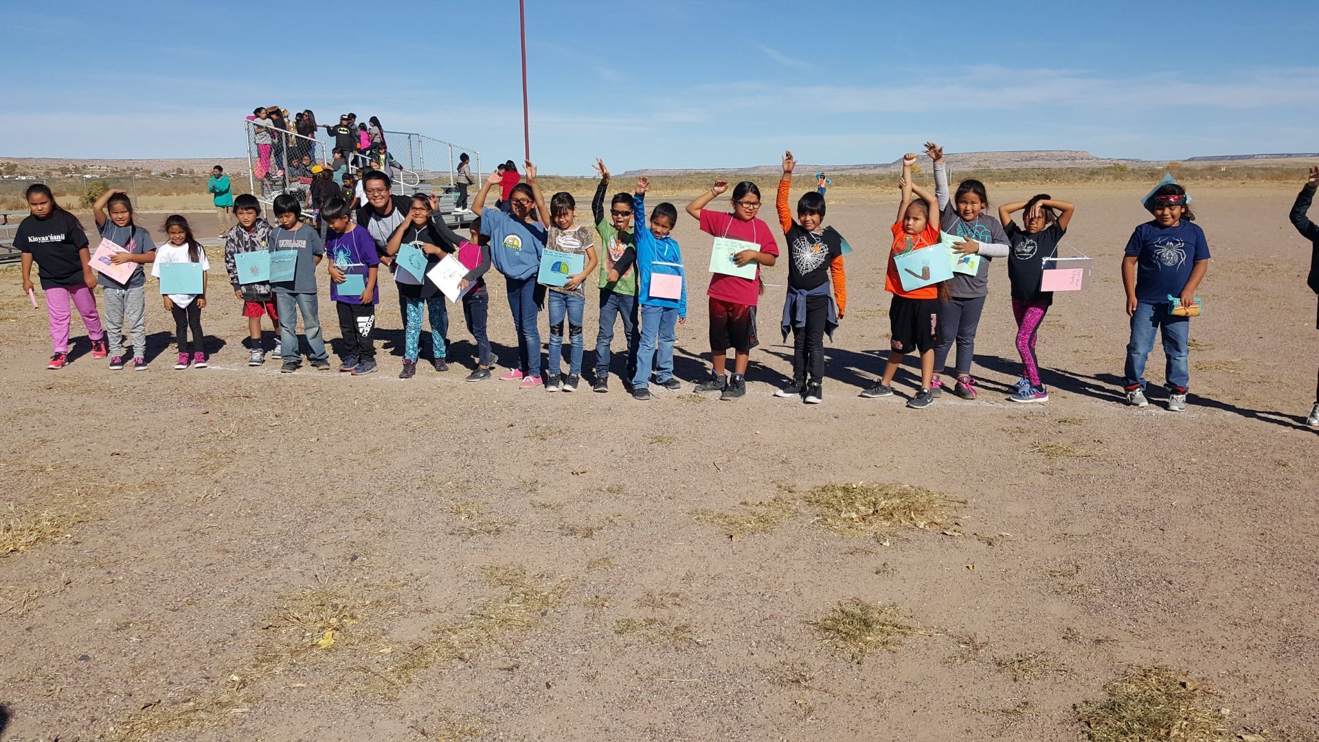 A group of children standing in a field with their hands in the air