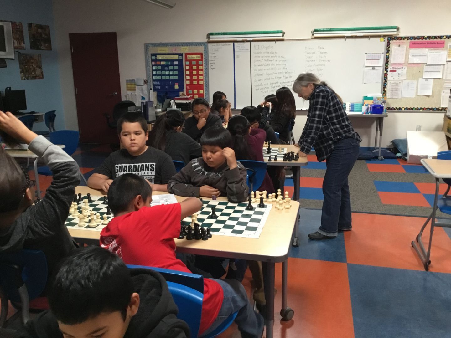 A group of children are playing chess in a classroom