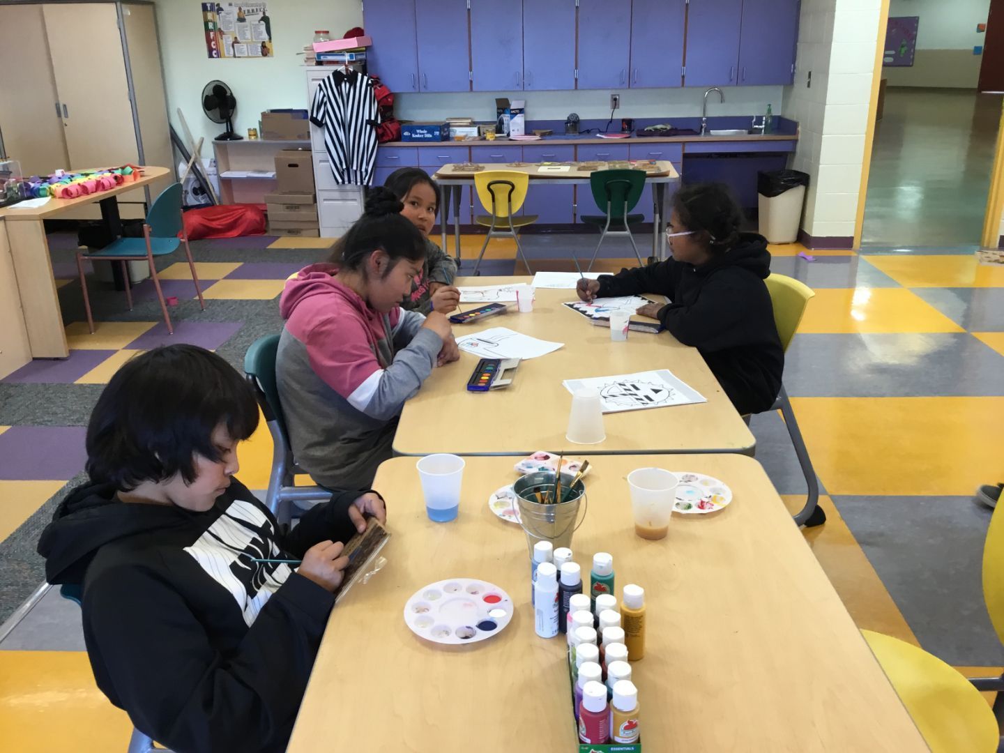 A group of children are sitting around a table painting