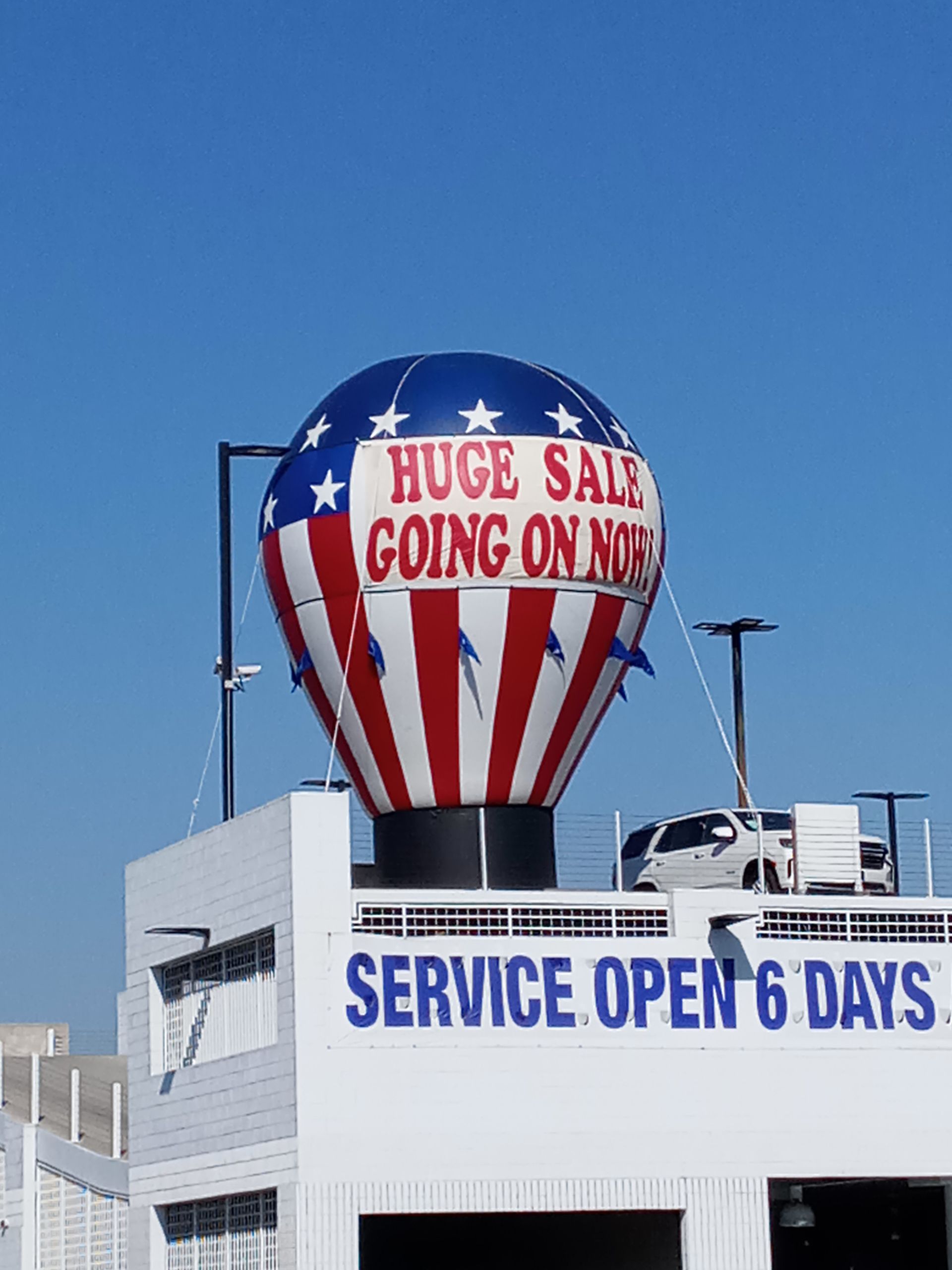 A hot air balloon on top of a building that says huge sale going on now