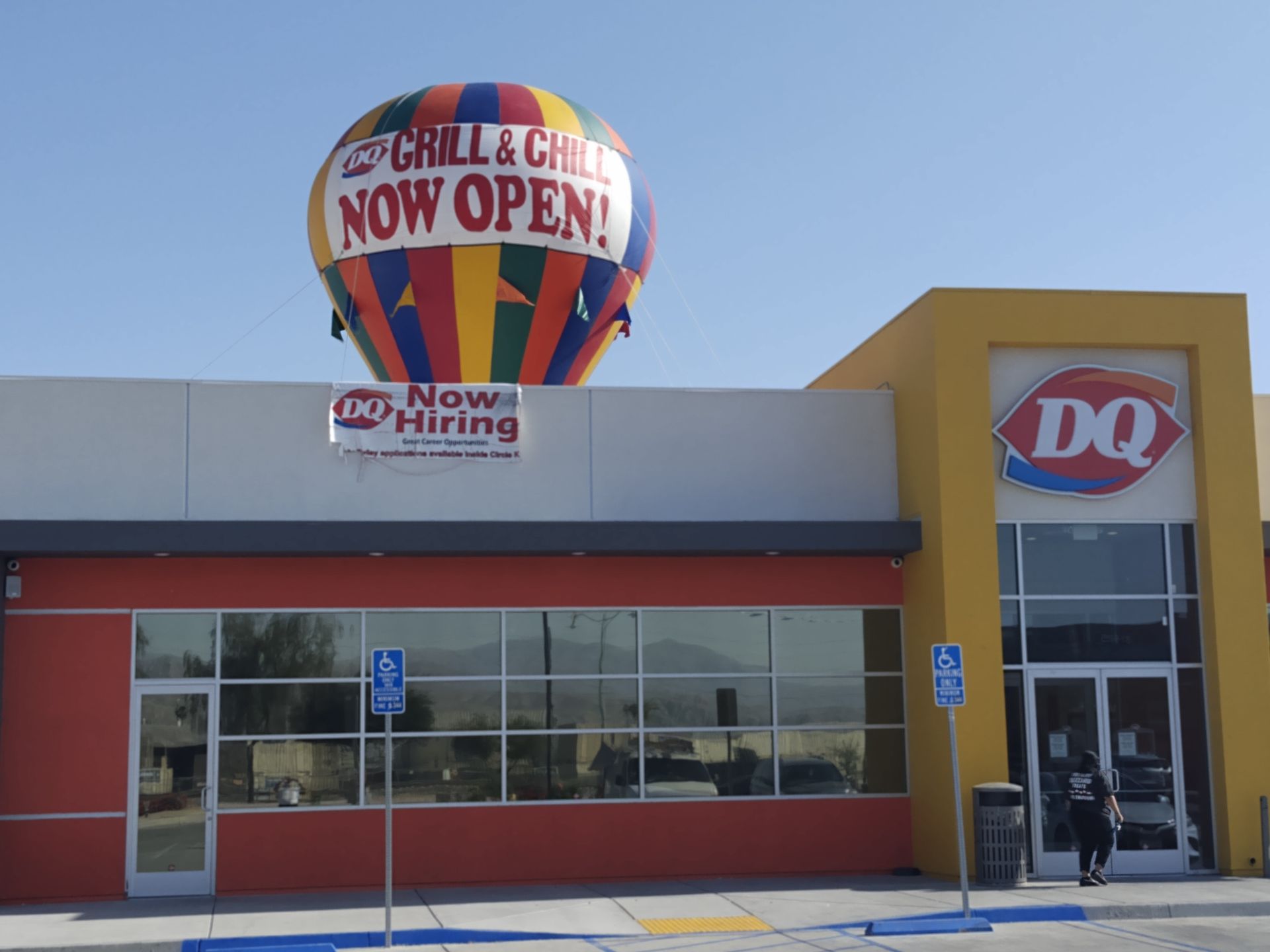 A hot air balloon above a dq restaurant says it is now open