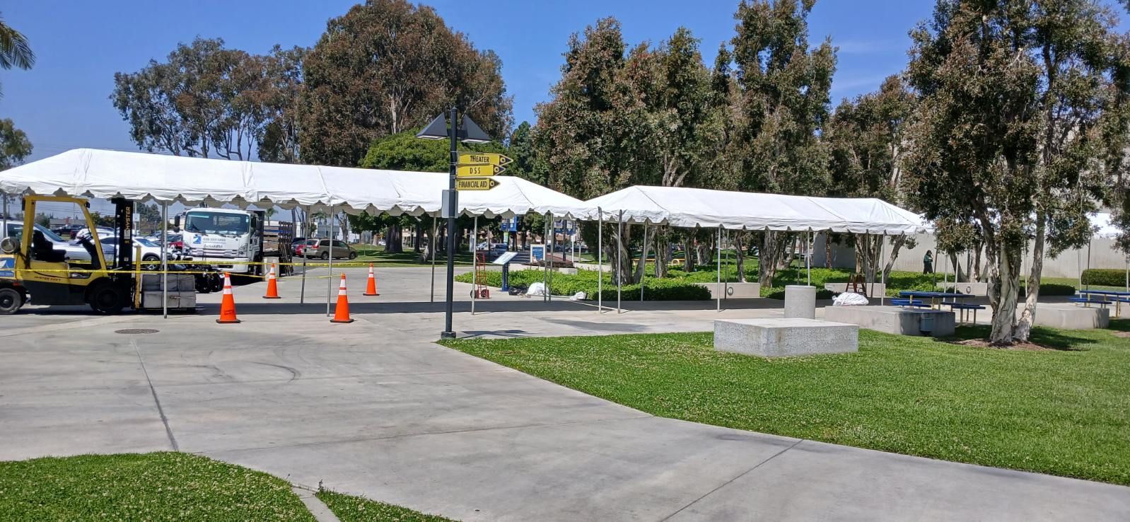 A large white tent is sitting in the middle of a park.