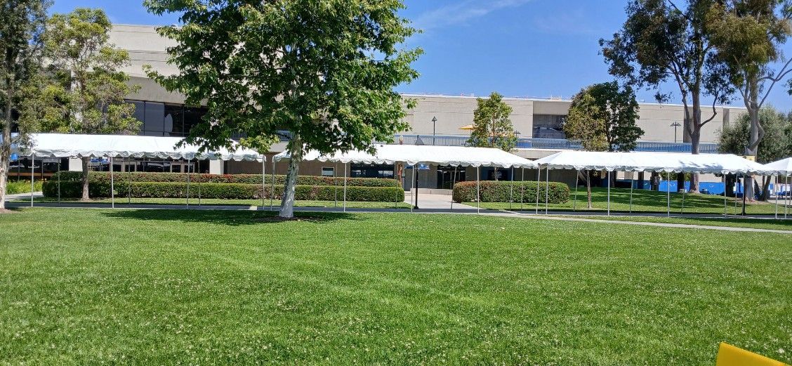 There are many tents in the grass in front of a building.