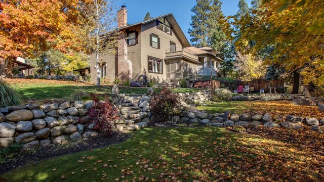 Stone house with autumn trees and a landscaped garden behind a rock retaining wall