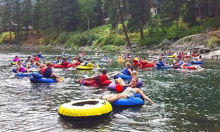 People floating on colorful inner tubes in a forest river