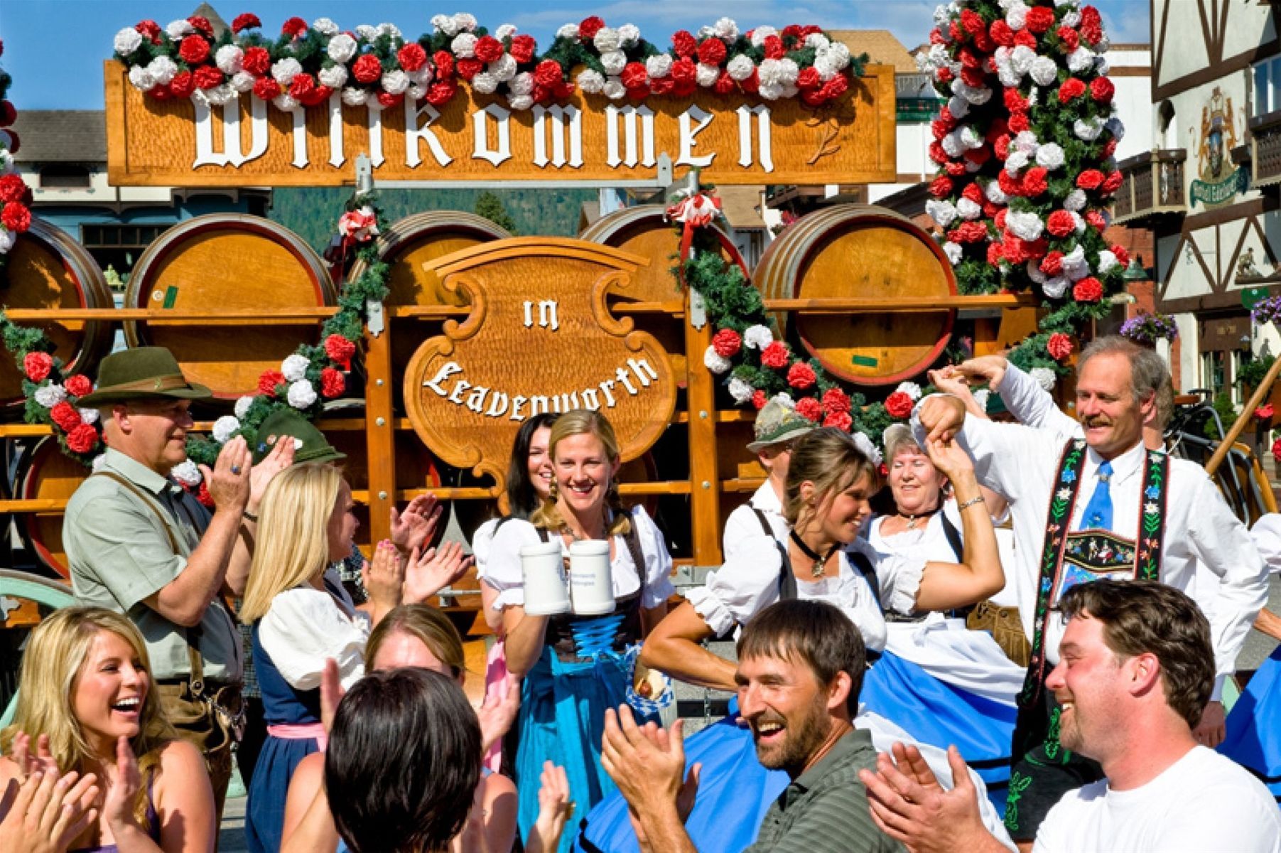 Crowd clapping at a festive beer tent with dancers and flower garlands