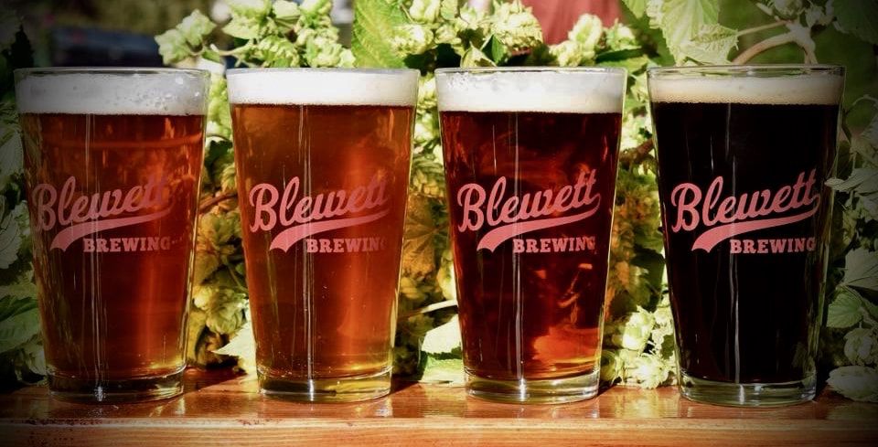 Four Bluerut Brewing beer glasses in amber, red, and dark pours on a wooden table.