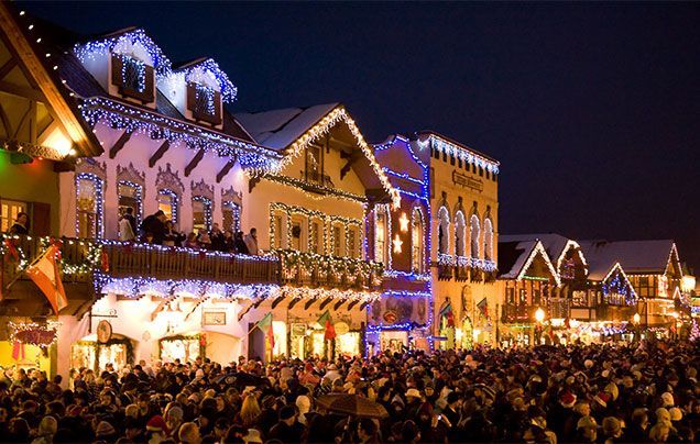 Crowded festive street at night with lit historic buildings and glowing holiday decorations