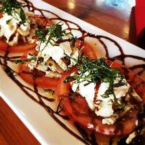 Three plated appetizers topped with herbs and drizzled sauce on a white serving dish