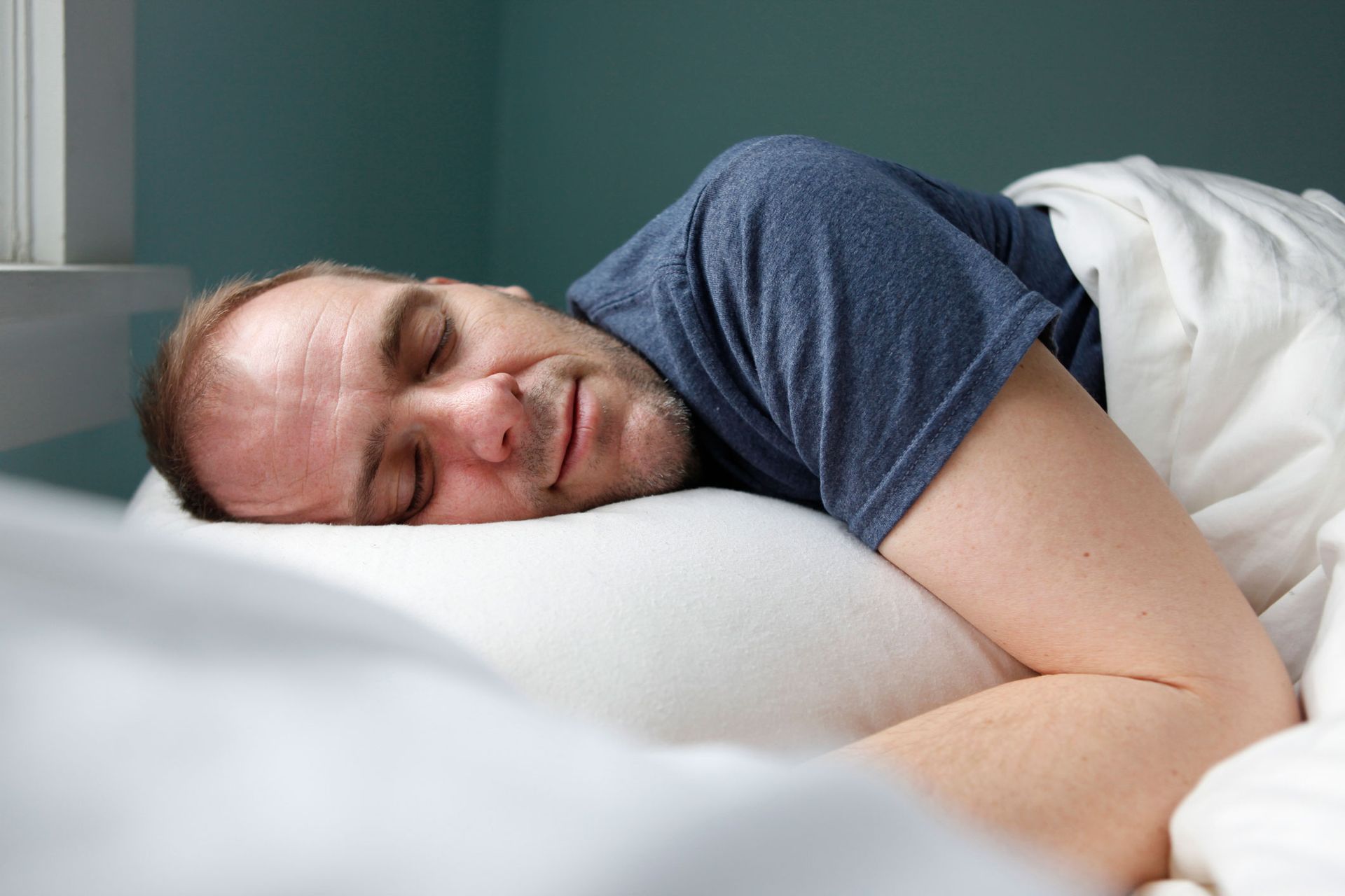 A man is sleeping on a bed with his head on a pillow. A man is sleeping on a bed with his head on a pillow.