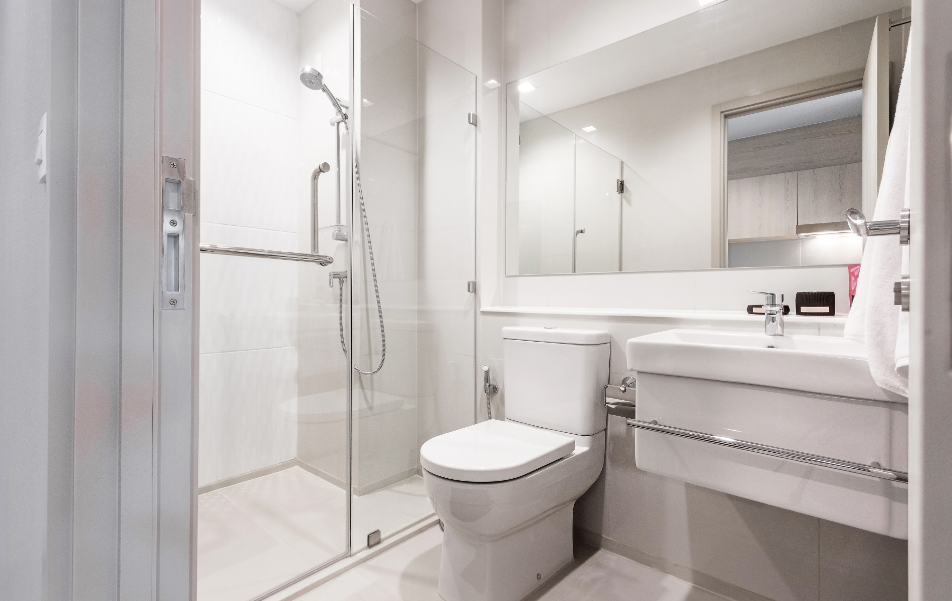 A bathroom with a toilet , sink , shower and mirror.