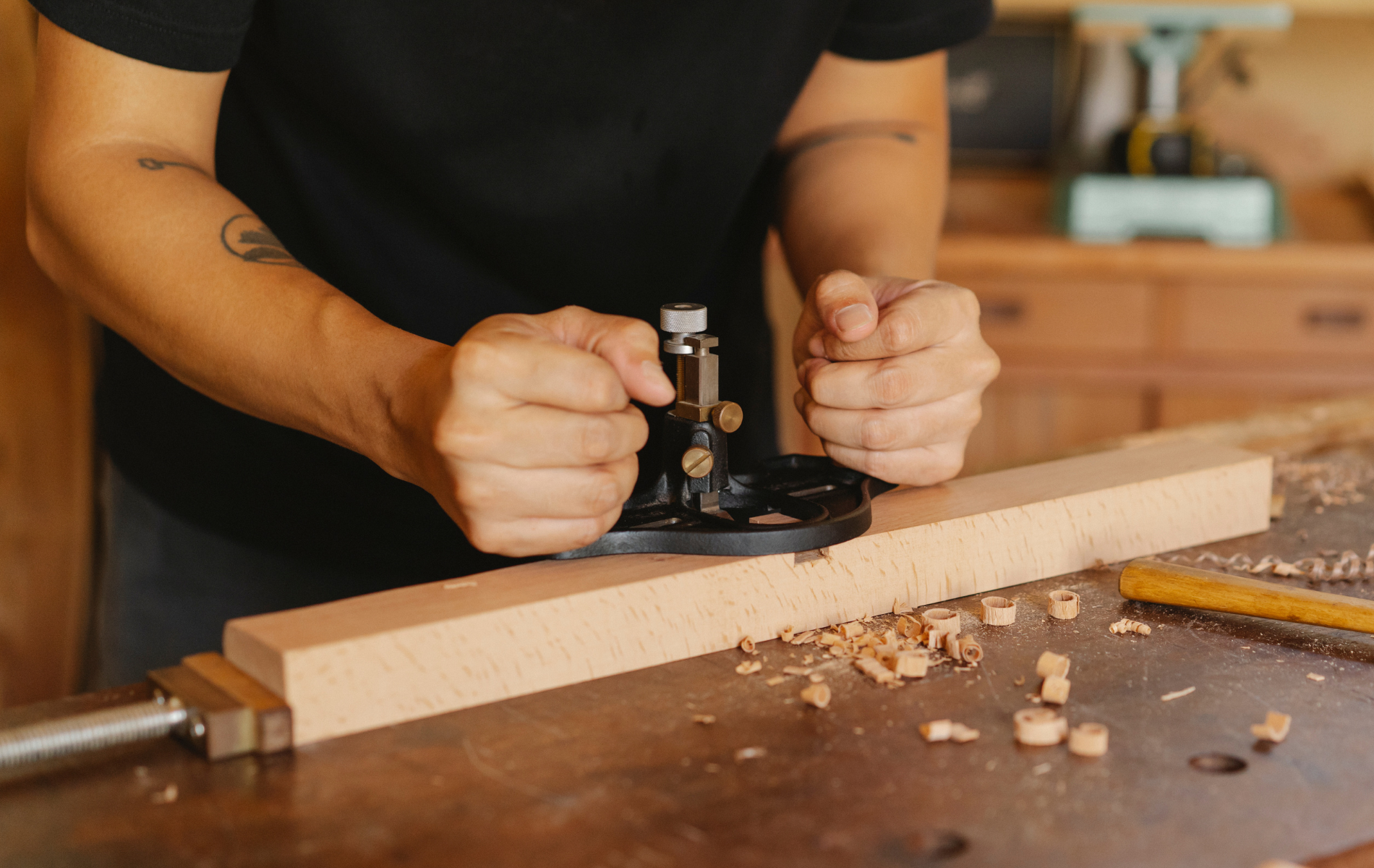 A man is using a plane to plane a piece of wood.