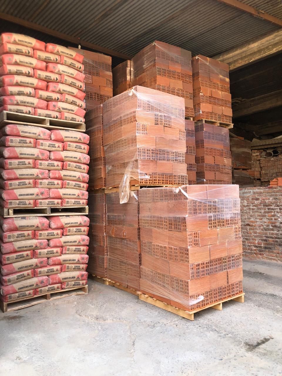 Ladrillos de arcilla roja apilados en una obra de construcción sobre terreno de tierra.
