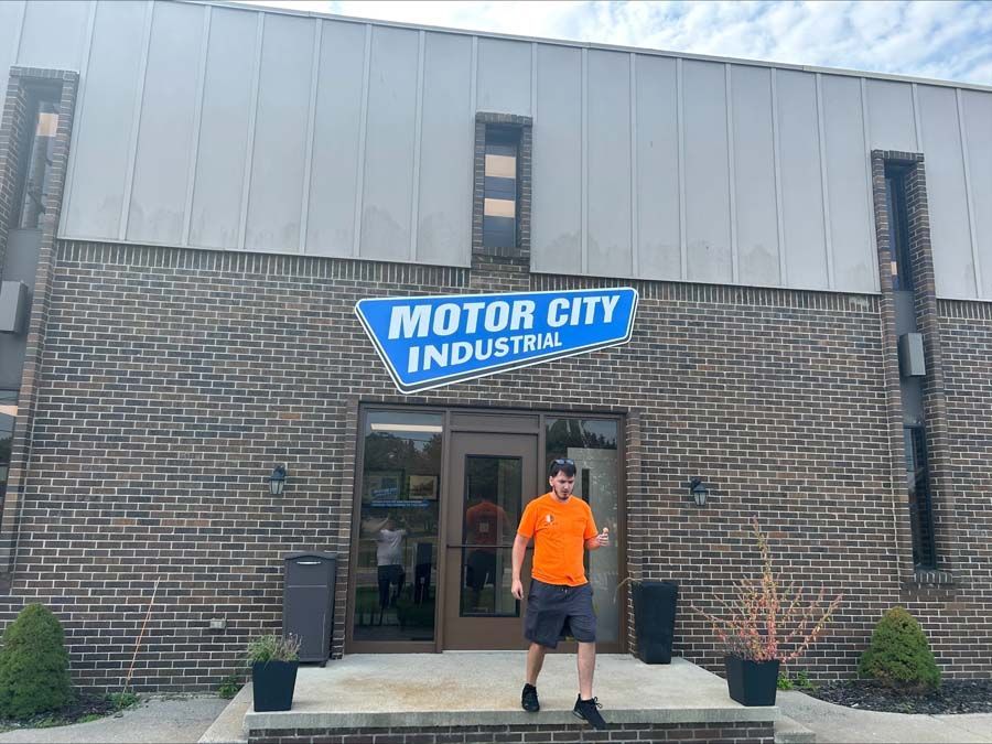 A person in an orange shirt exits a brick building labeled 