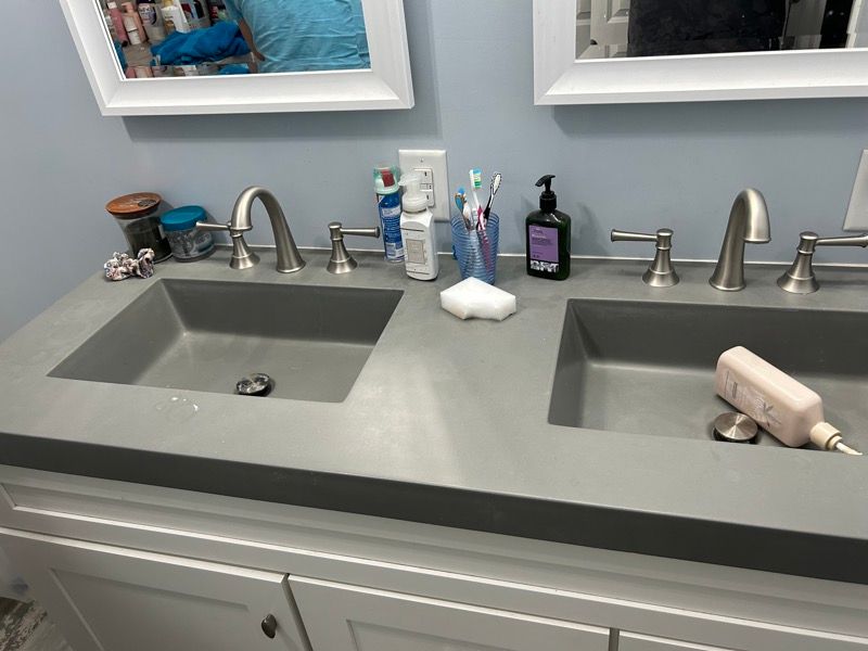 A modern double-sink bathroom vanity with light gray counters, white cabinets, and chrome fixtures.