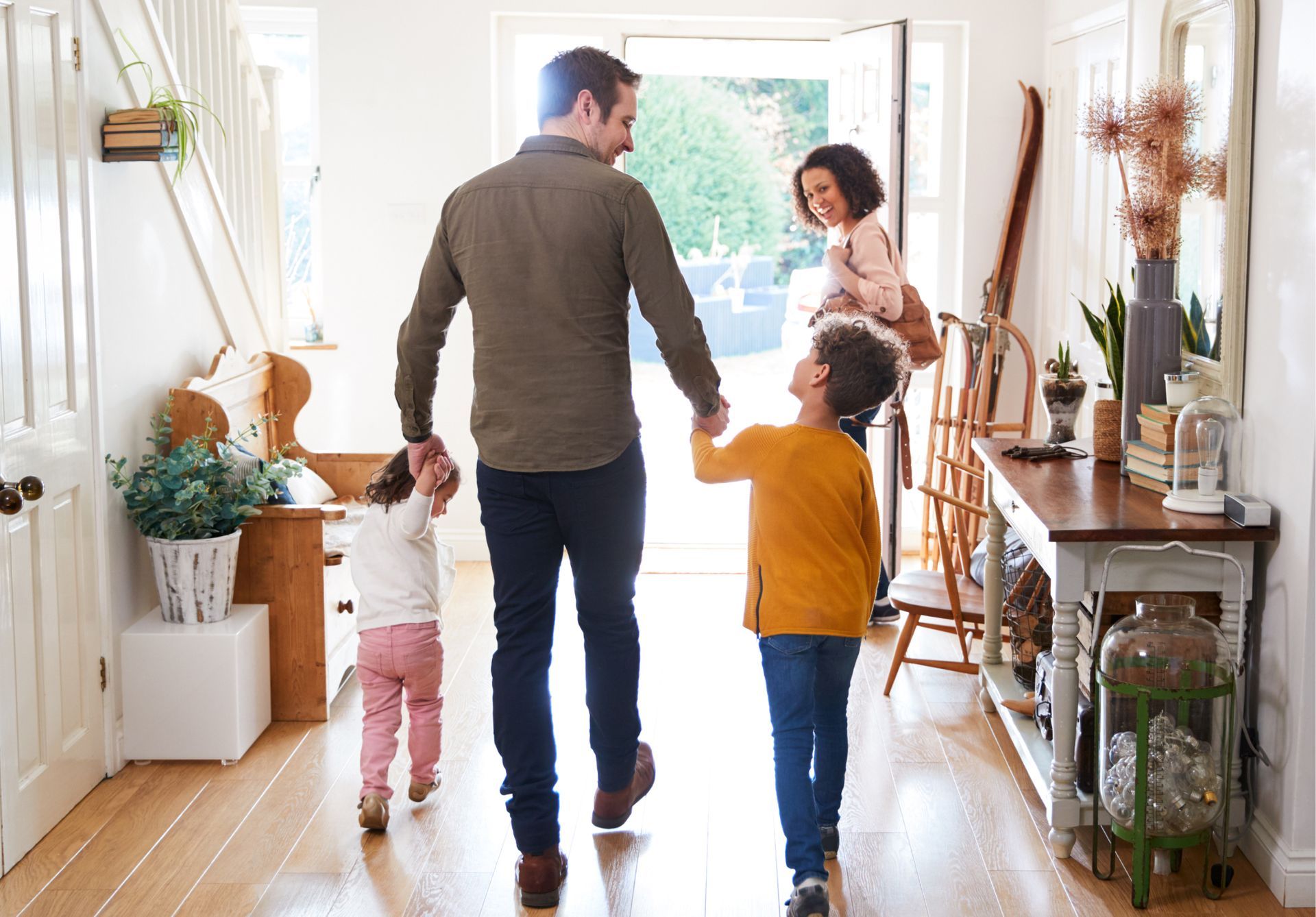 A family is walking down a hallway holding hands.