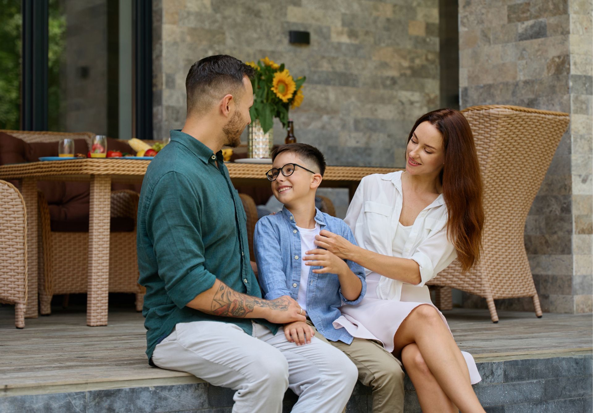 A family is sitting on a porch talking to each other.