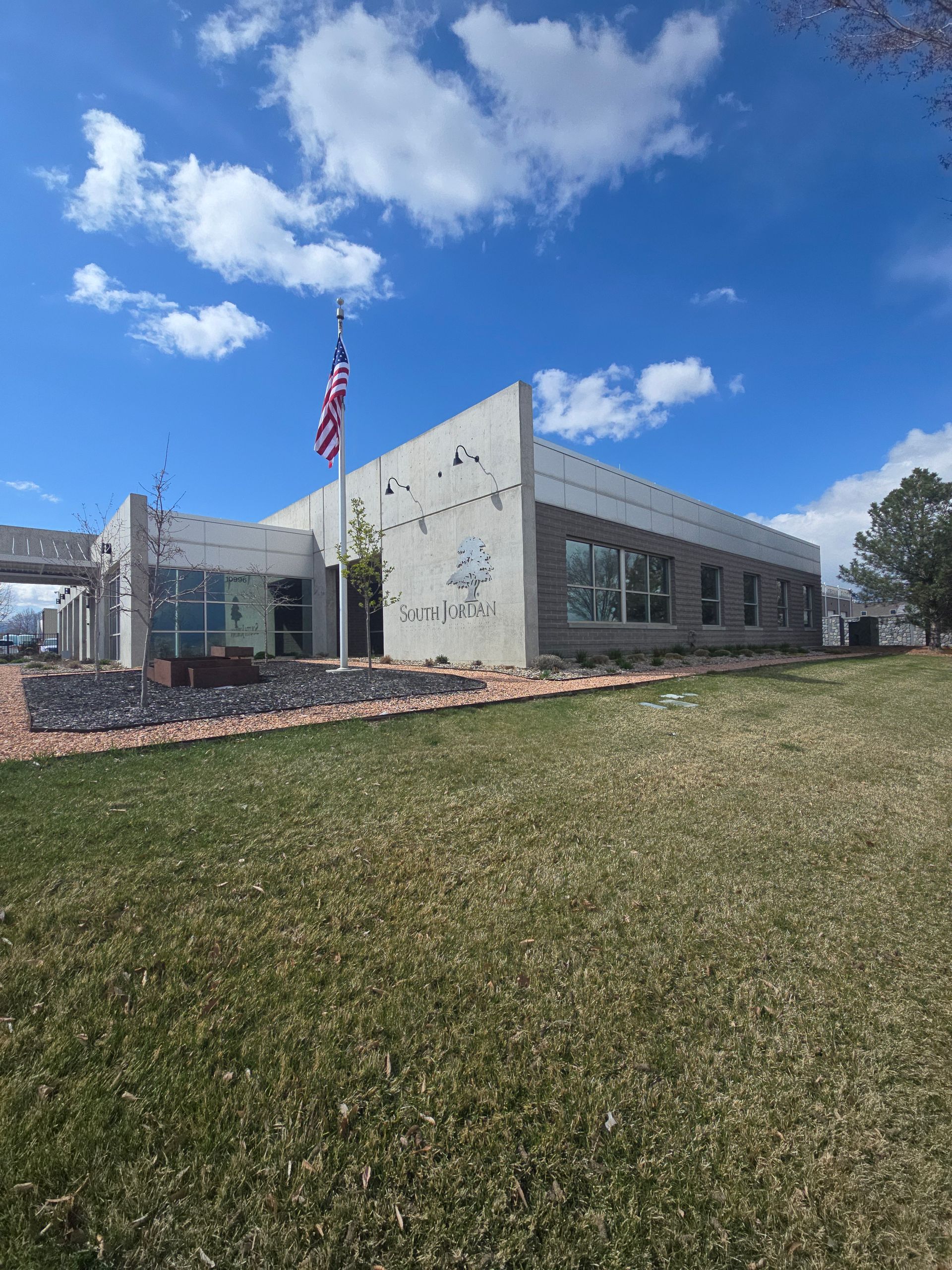 Brick building with large windows reflecting sky and a white pickup truck parked in front.