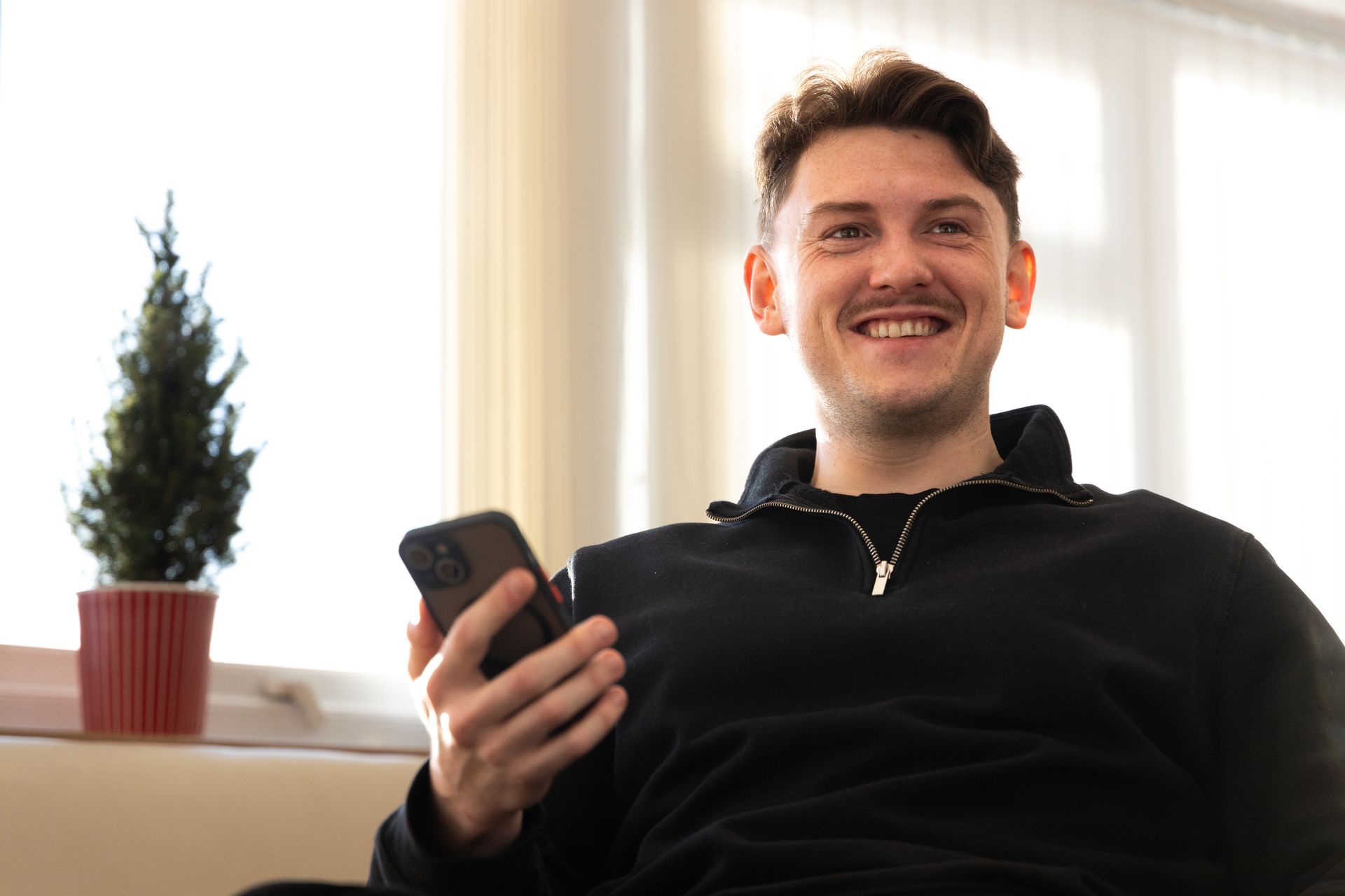 A man is sitting on a bean bag chair holding a cell phone.