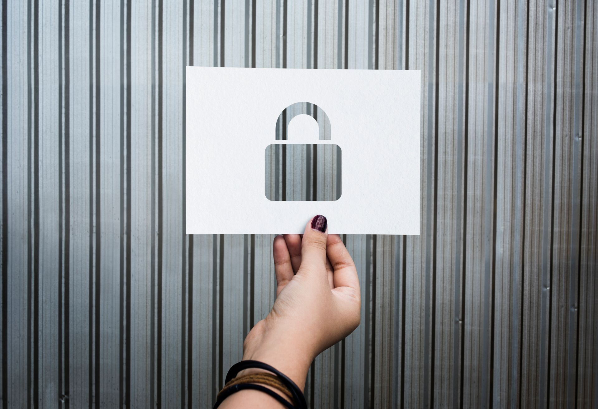 A person is holding a piece of paper with a padlock cut out of it.