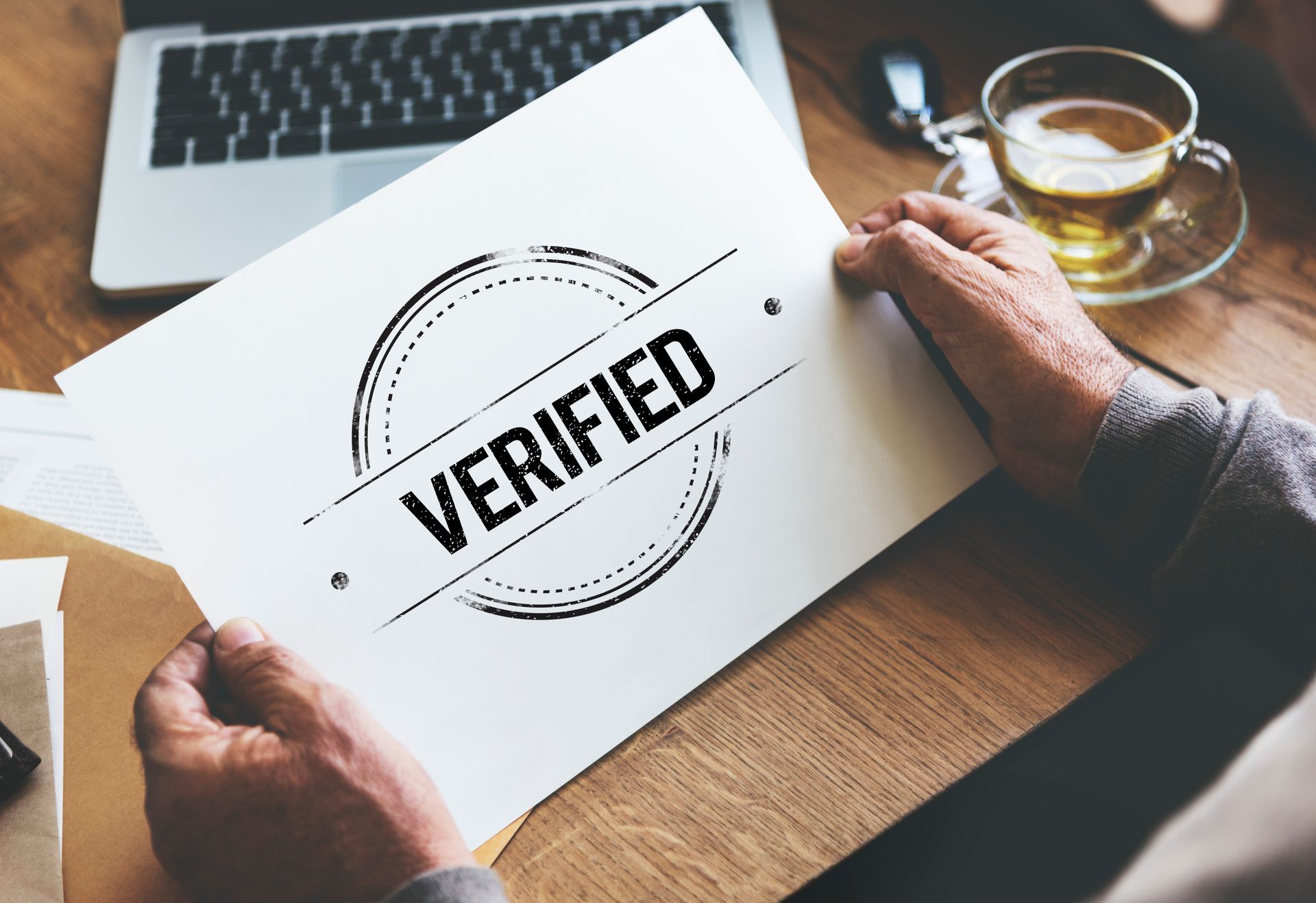 A person is holding a piece of paper that says verified on it.