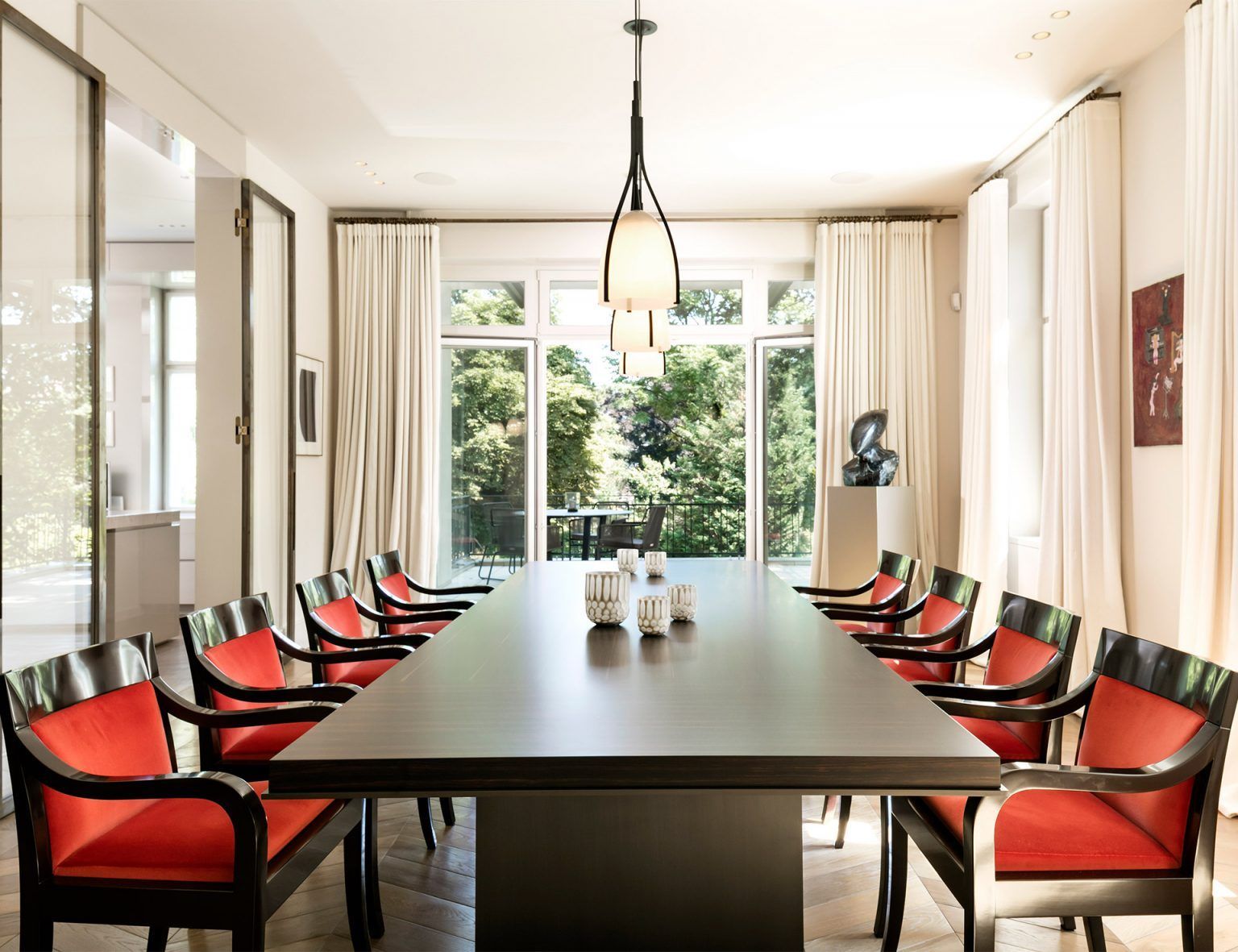 Ein Esszimmer mit einem langen Tisch und roten Stühlen