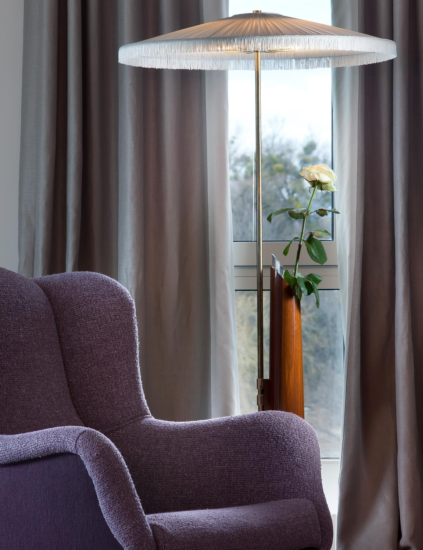 Ein lila Stuhl und eine Lampe vor einem Fenster