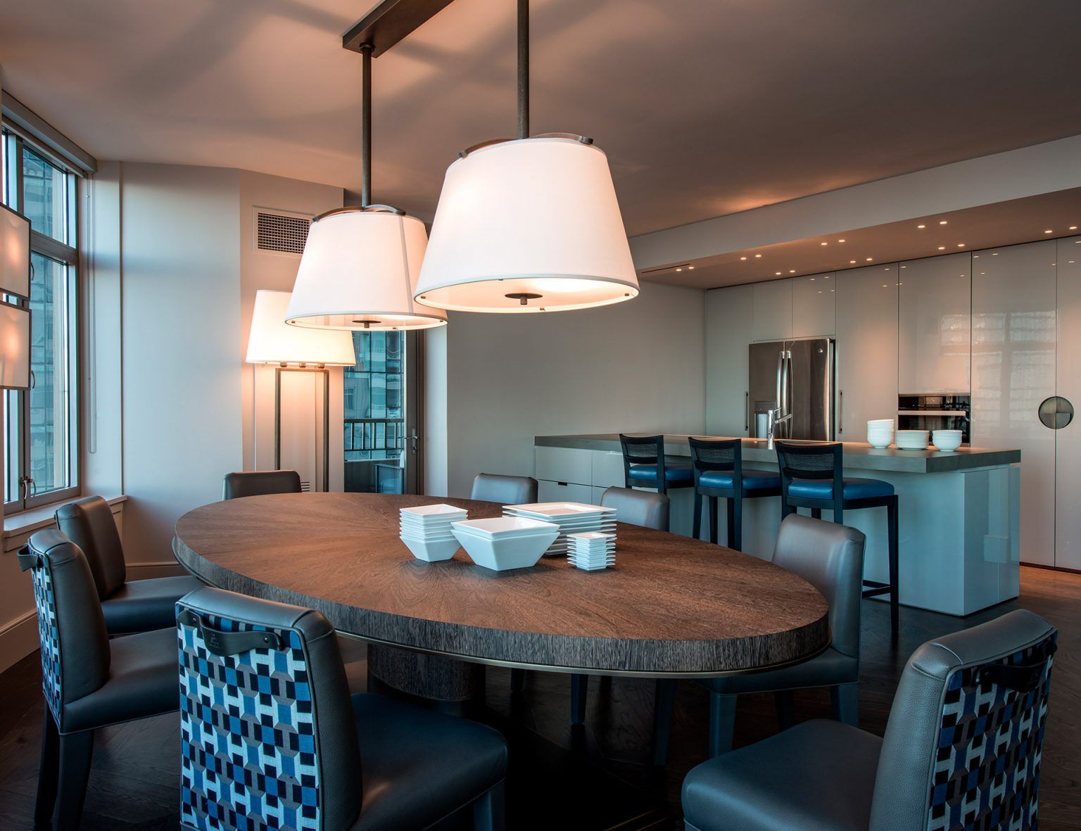 Ein Esszimmer mit großem Tisch und Stühlen und einer Küche im Hintergrund.