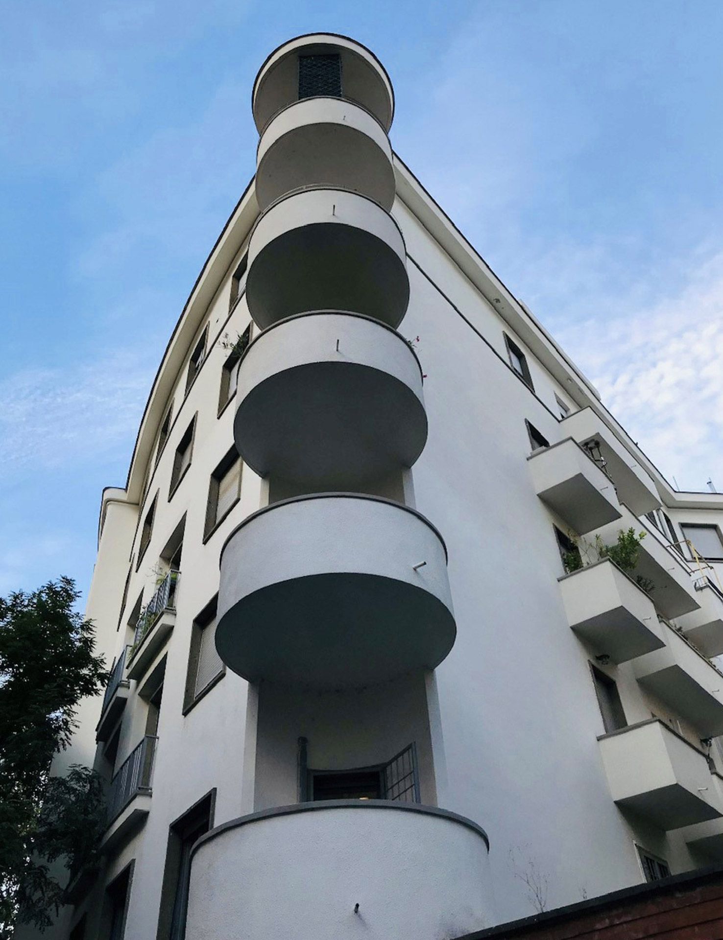 Blick nach oben auf ein hohes weißes Gebäude mit Balkonen