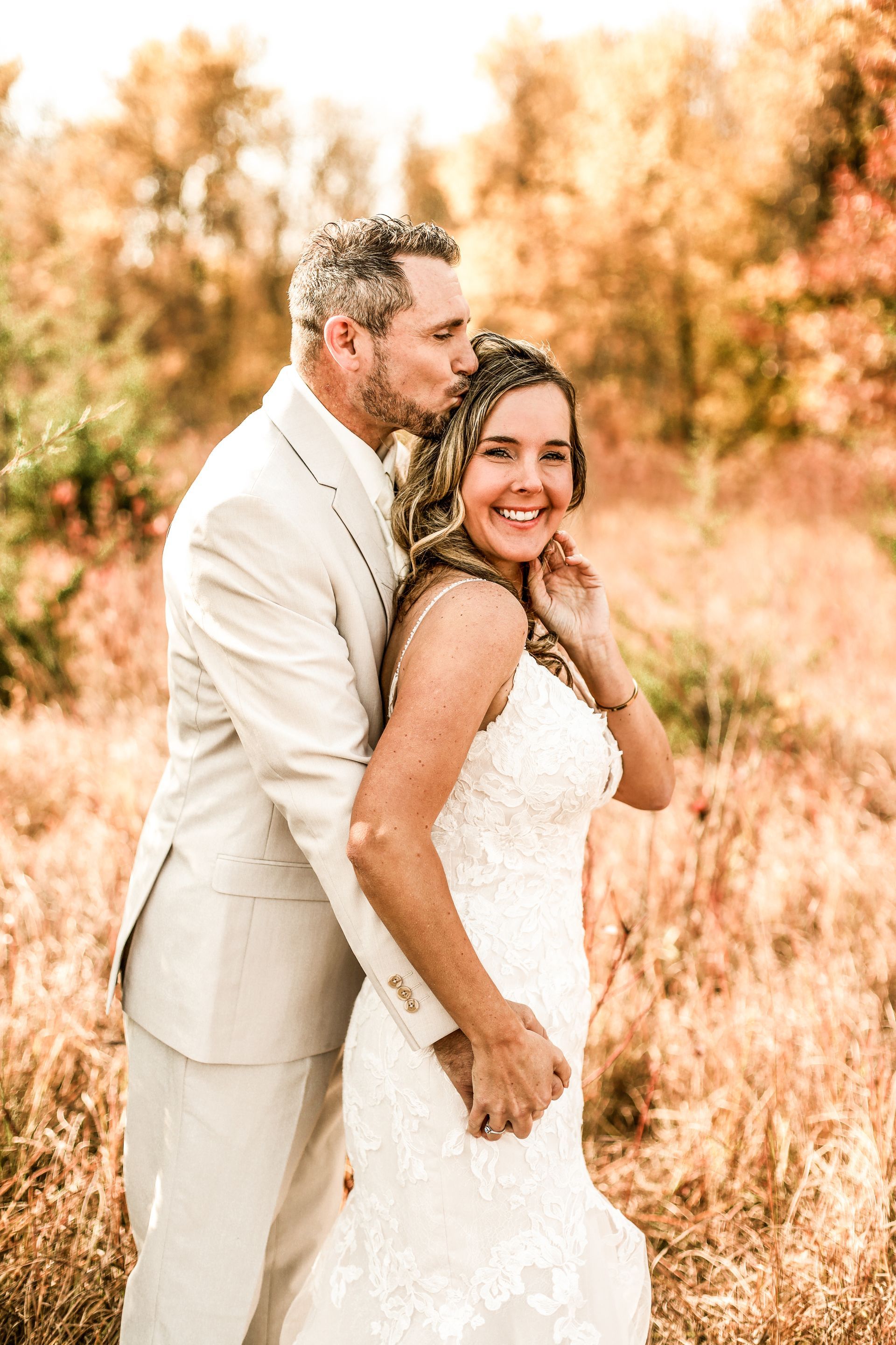 A man and a woman are kissing in a field near a river.