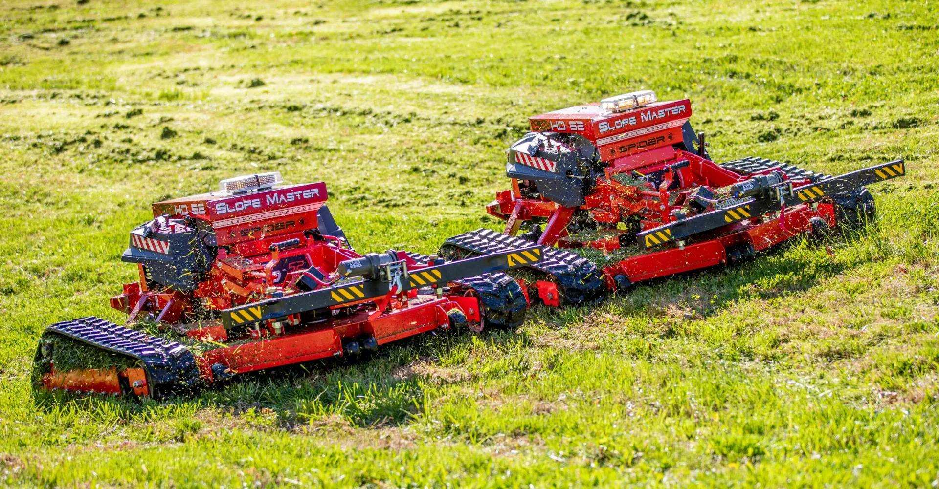 Two red and black robotic-looking vehicles on grassy field.