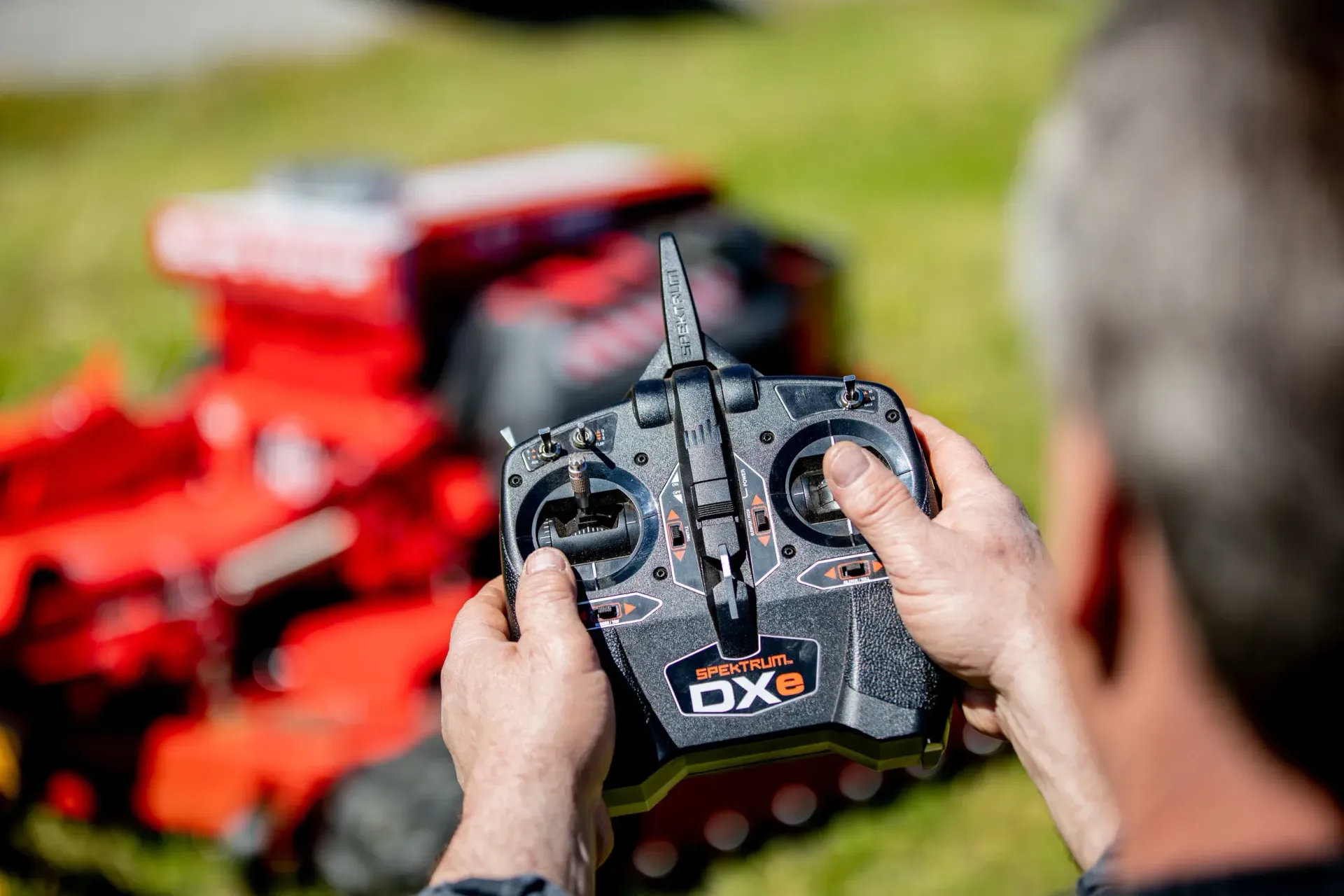 Slope Master Remote Control being used by a jmower to operate a slope mowr in the background.