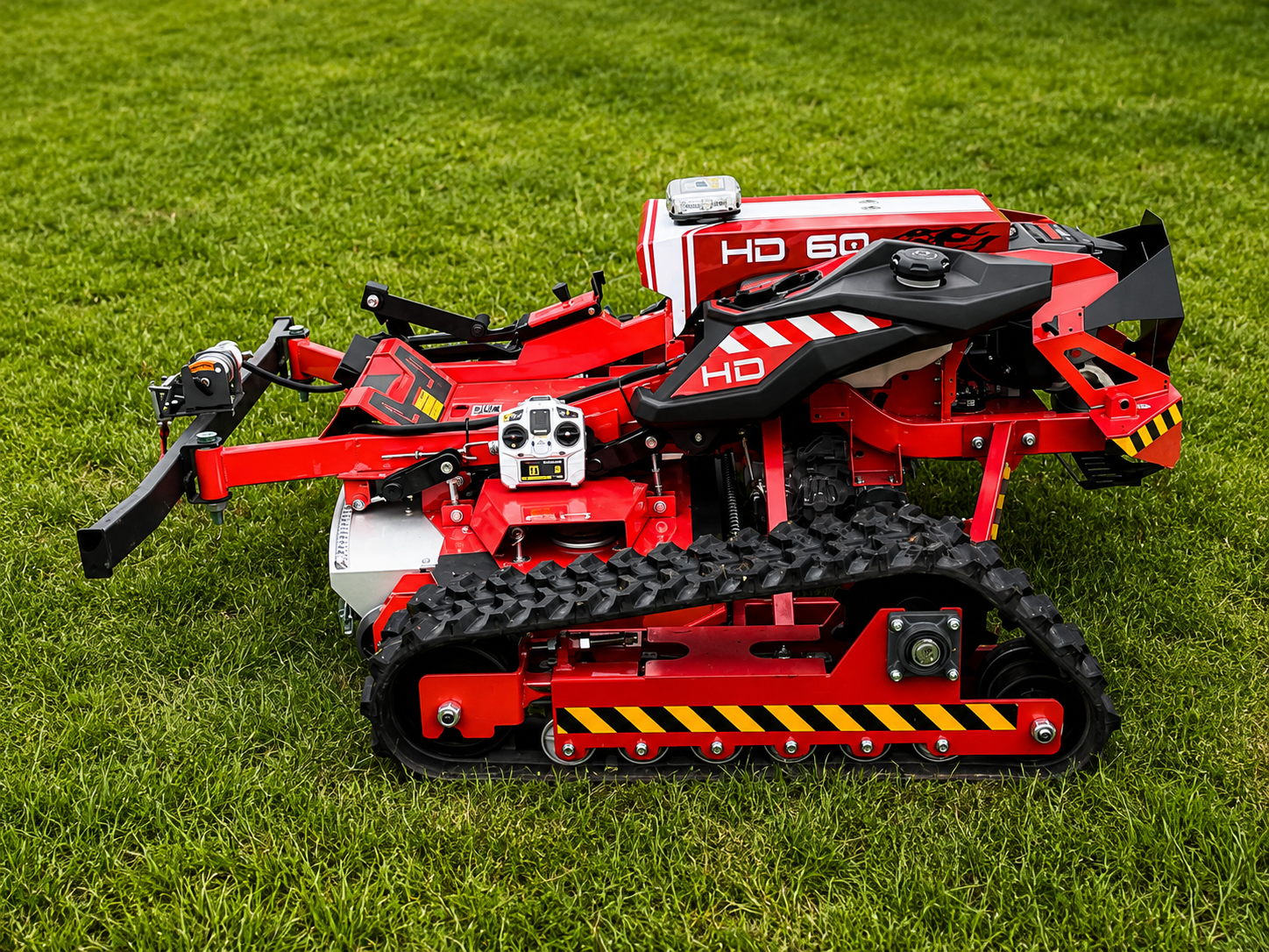 Exlore Our Technology Red tracked RC construction vehicle on grass, with black arms and hazard-striped front bumper.