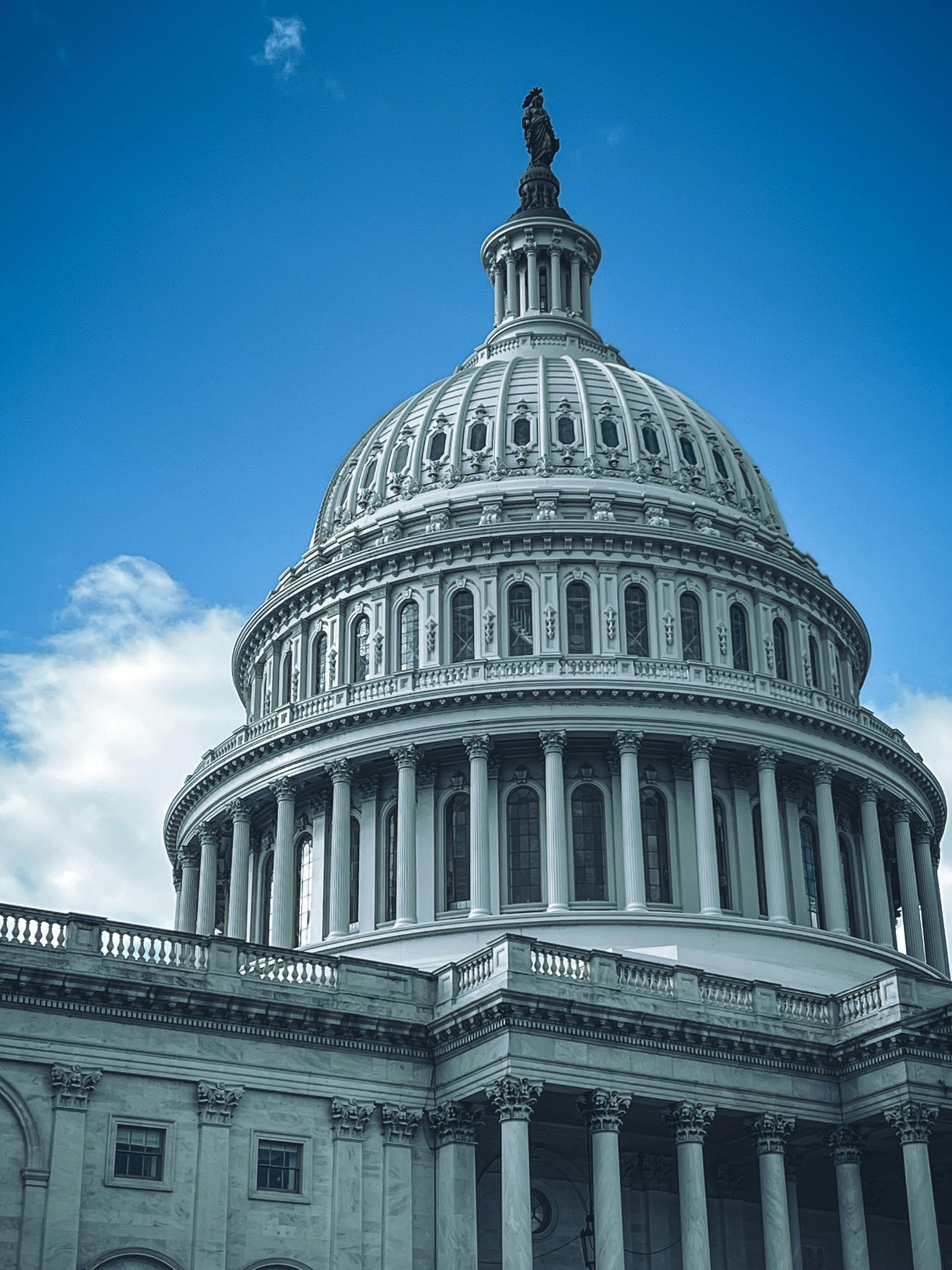 U.S. Capitol dome against a blue sky with white clouds