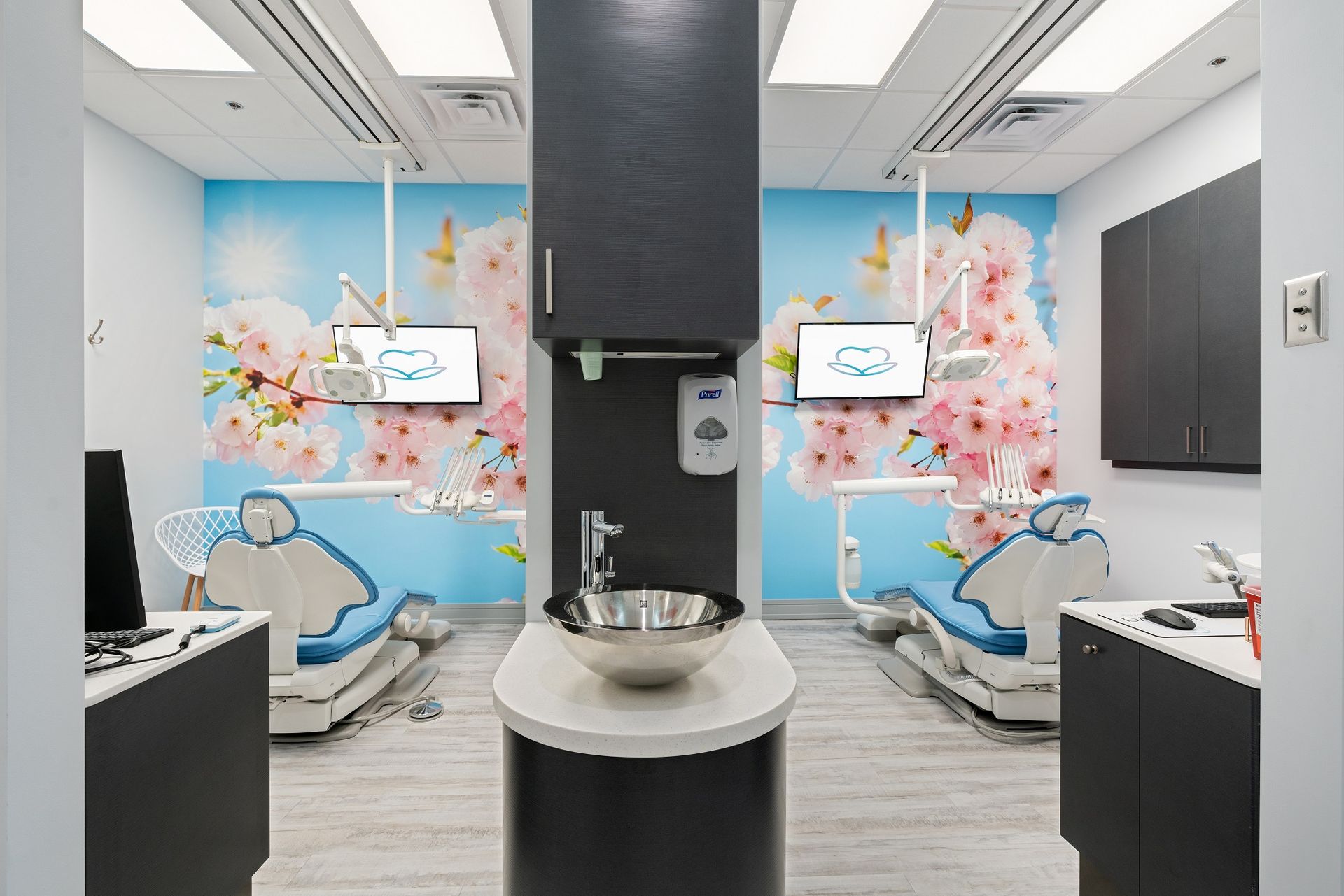 A dental office with two dental chairs and a sink.