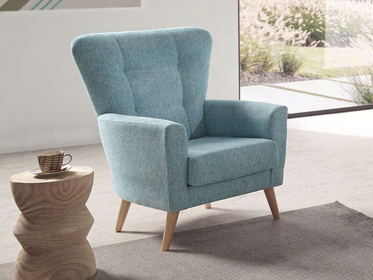 a blue chair is sitting next to a wooden table with a cup of coffee on it .