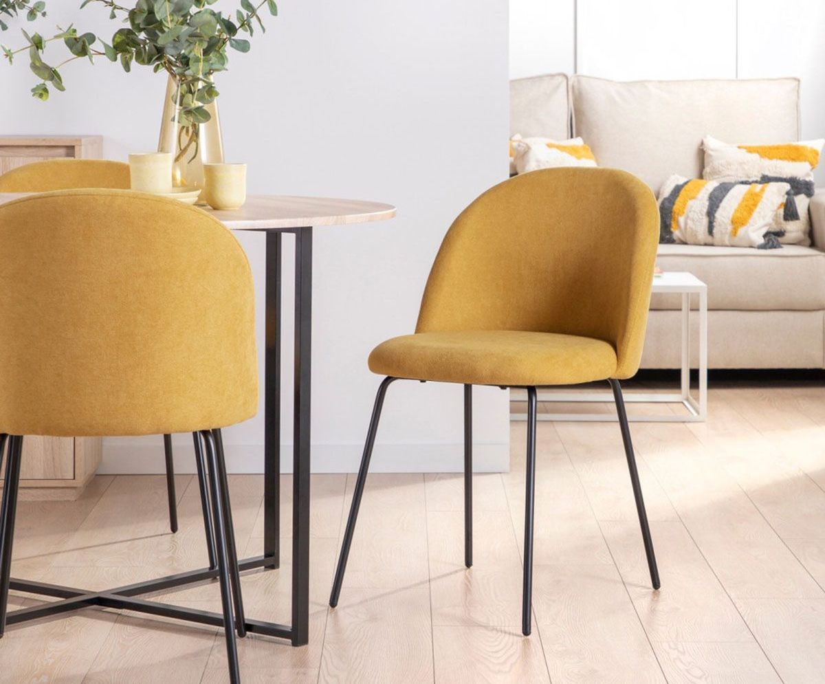 a yellow chair sits next to a table in a living room
